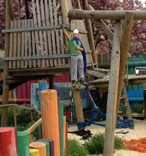 The image shows a child dressed up as a king standing on the play equipment