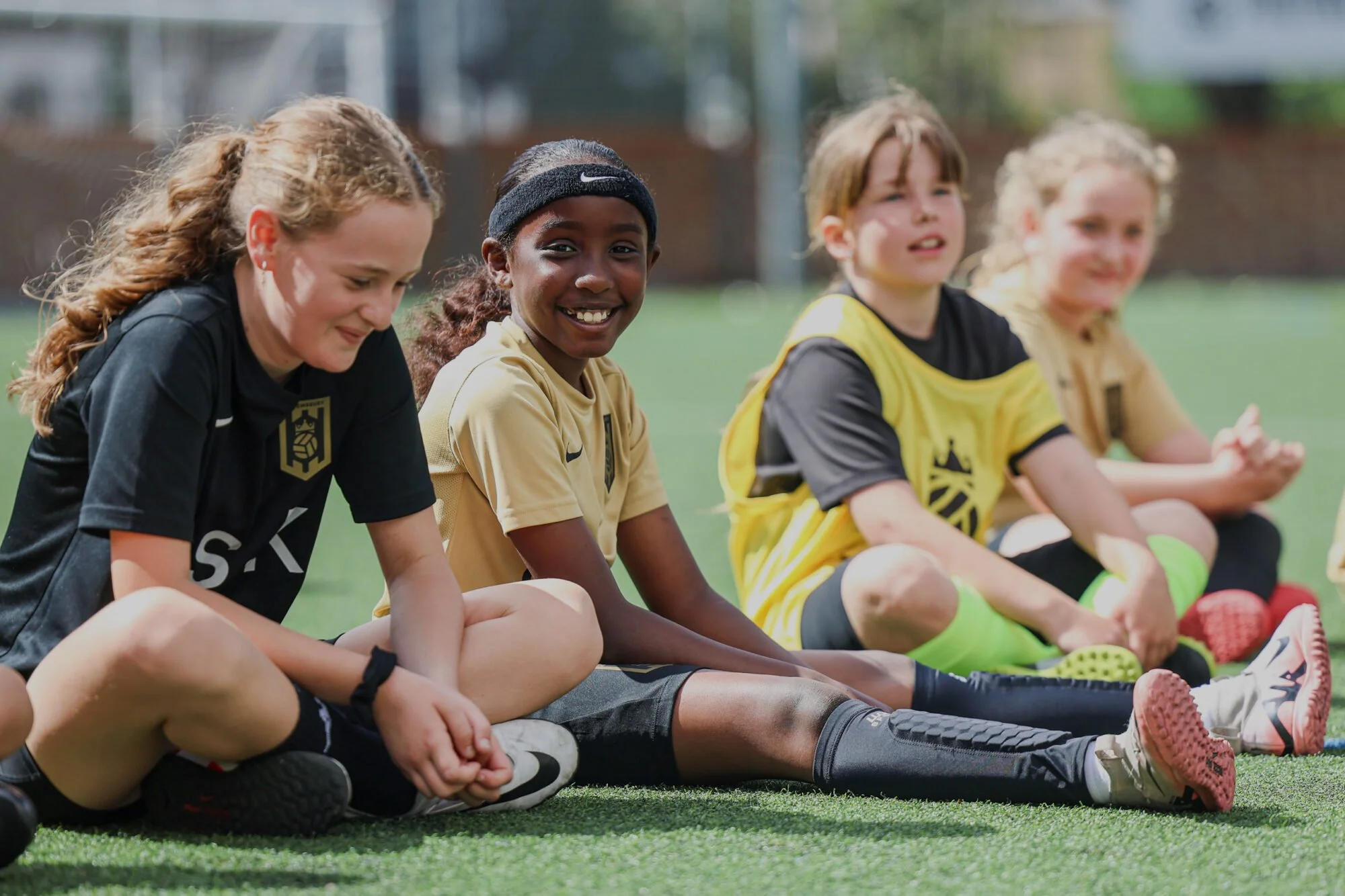The image shows four children seated wearing football kit