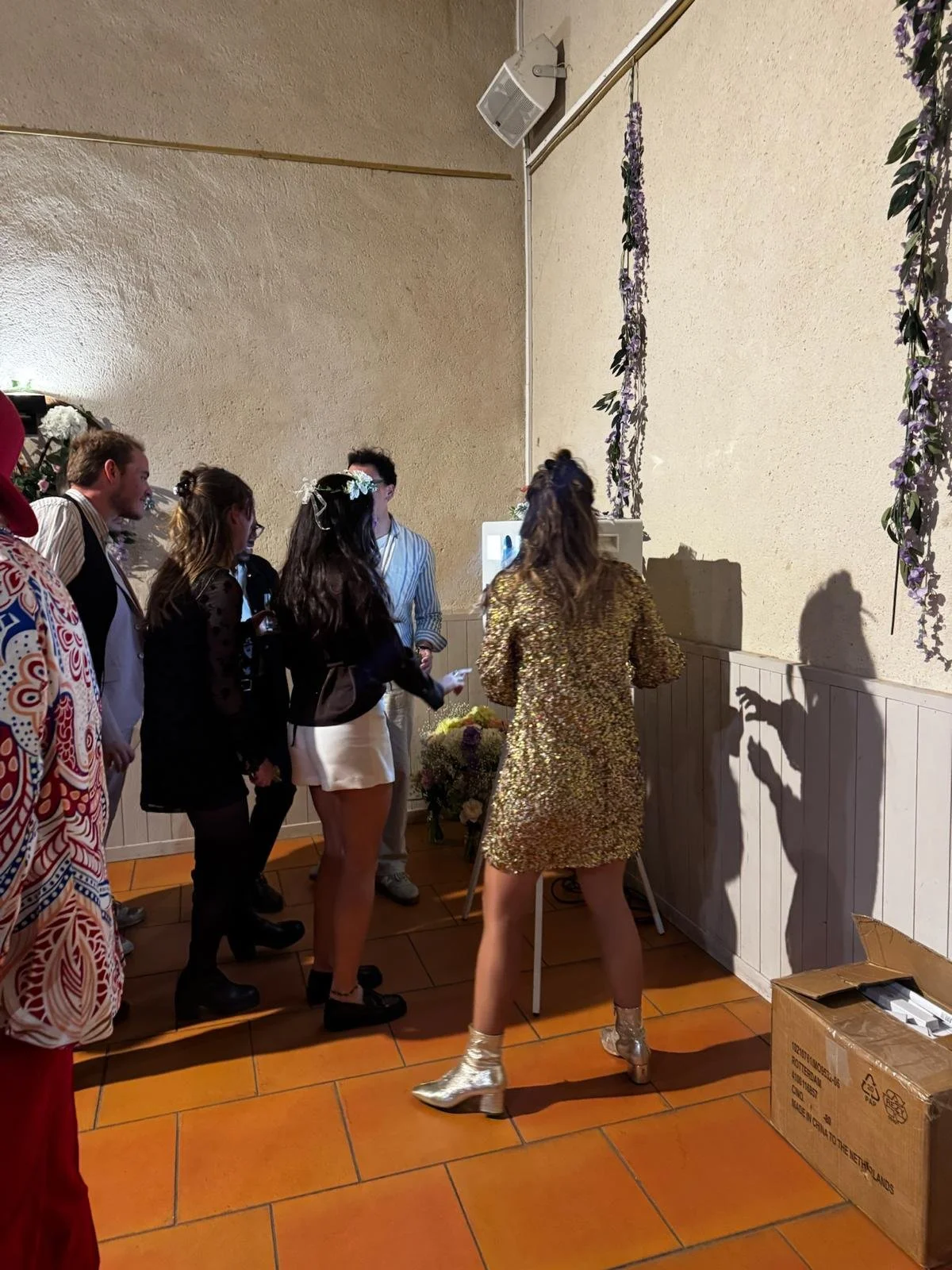 Photo en extérieur montrant une animation photobooth, sous un patio couvert. On voit un tonneau en bois à proximité avec des lunettes de soleil colorées posées dessus, pour l'animation photobooth.