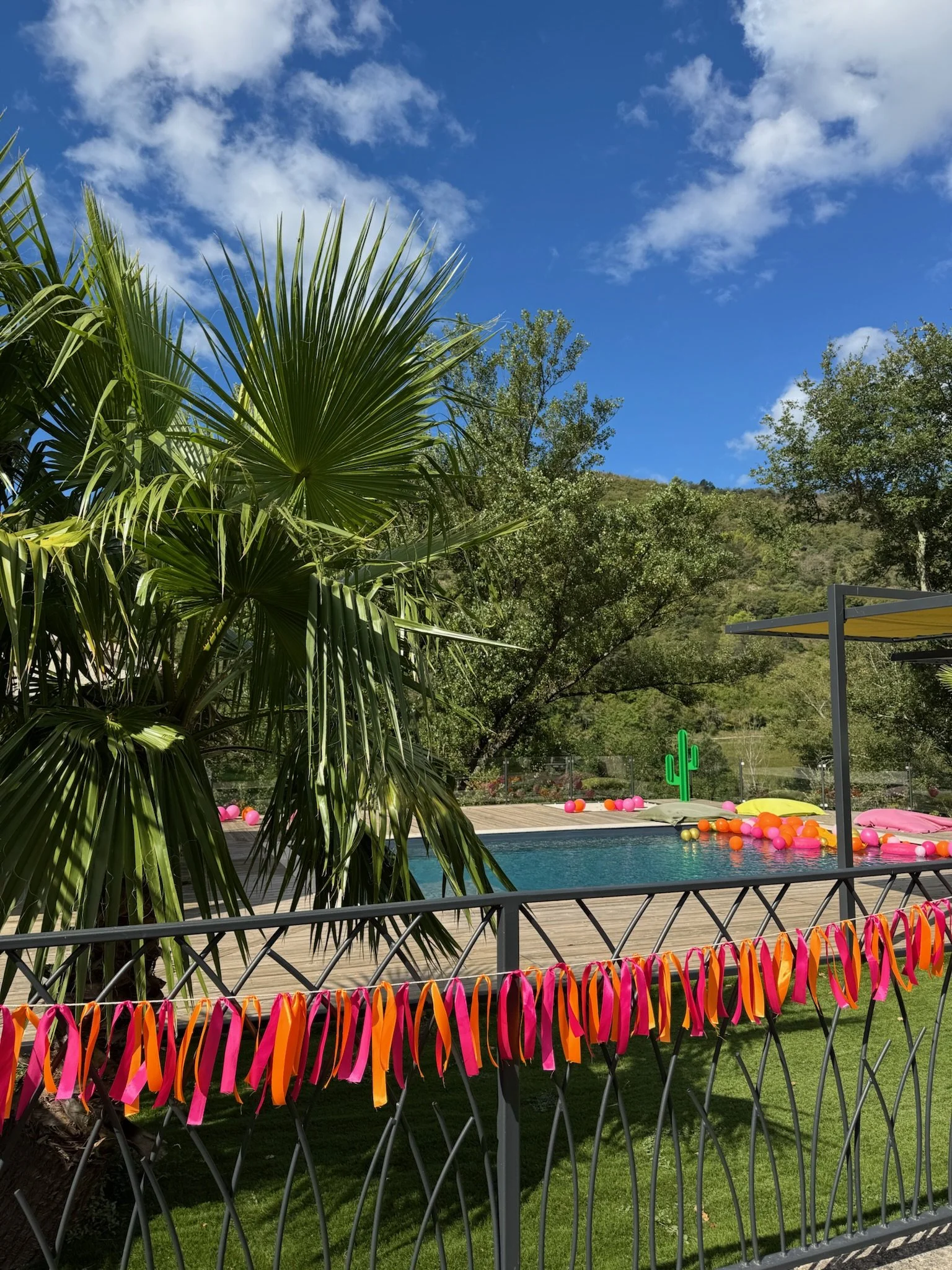 Décoration événementielle autour d’une piscine avec ballons colorés et rubans pour une célébration organisée par OE Agency