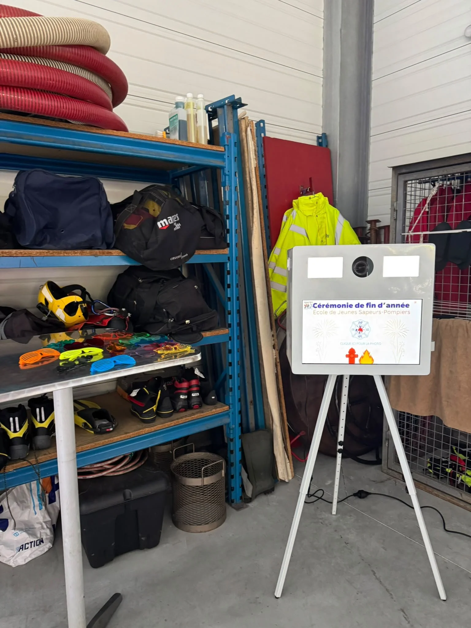 Storage area with ladders, bags, safety equipment, hoses, and a sign related to a fire safety ceremony.