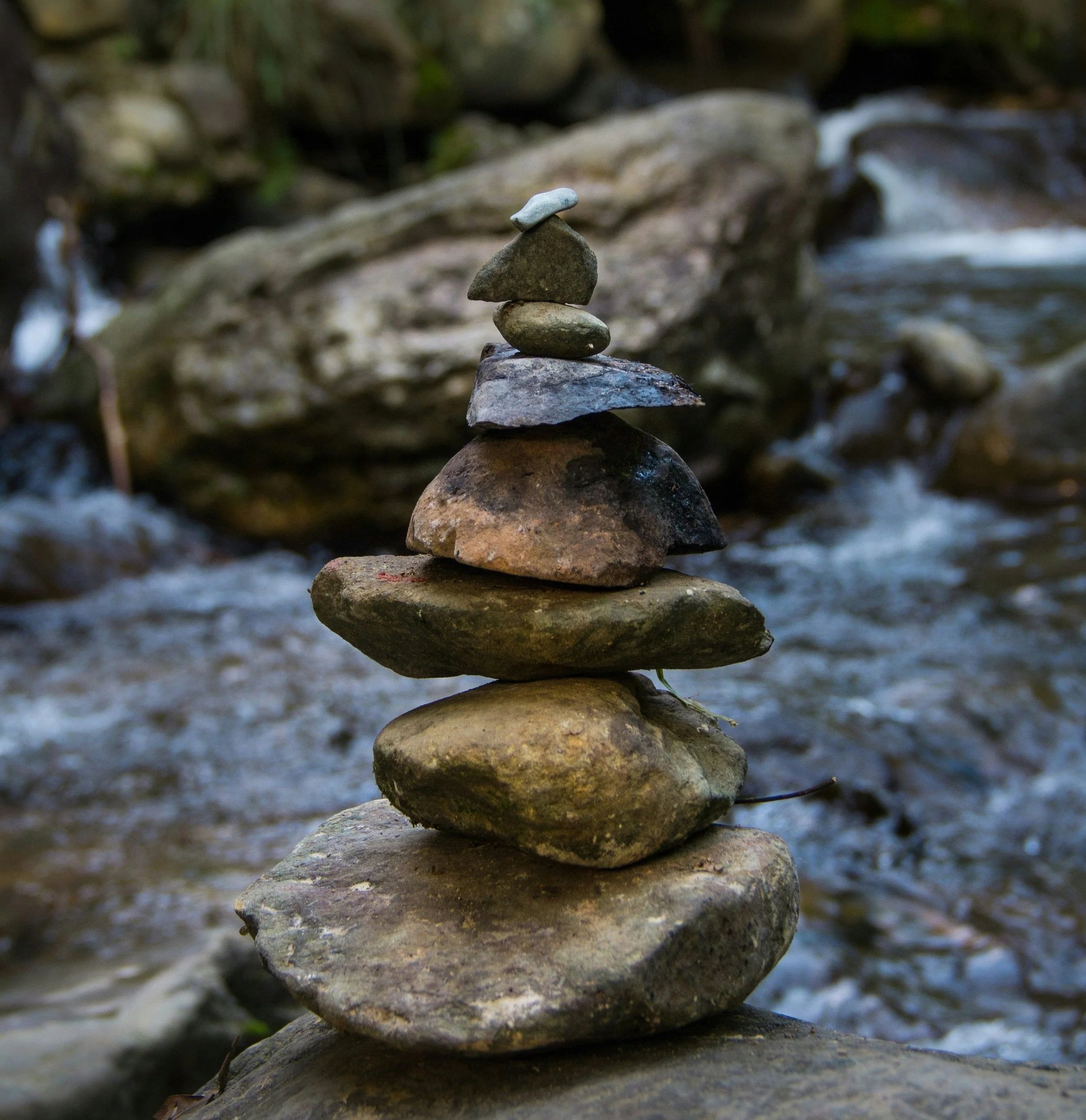 Eine Steinsäule aus mehreren flachen Steinen auf einem flachen Stein am Fluss.