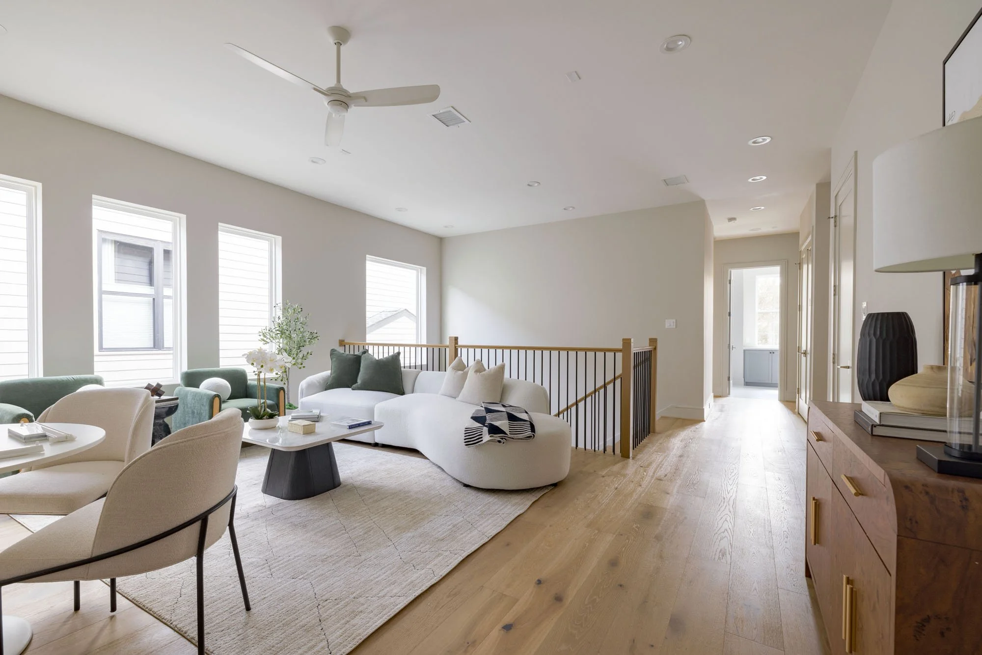 Upstairs game room with curved white sectional, green accent chairs, and open stair railing
