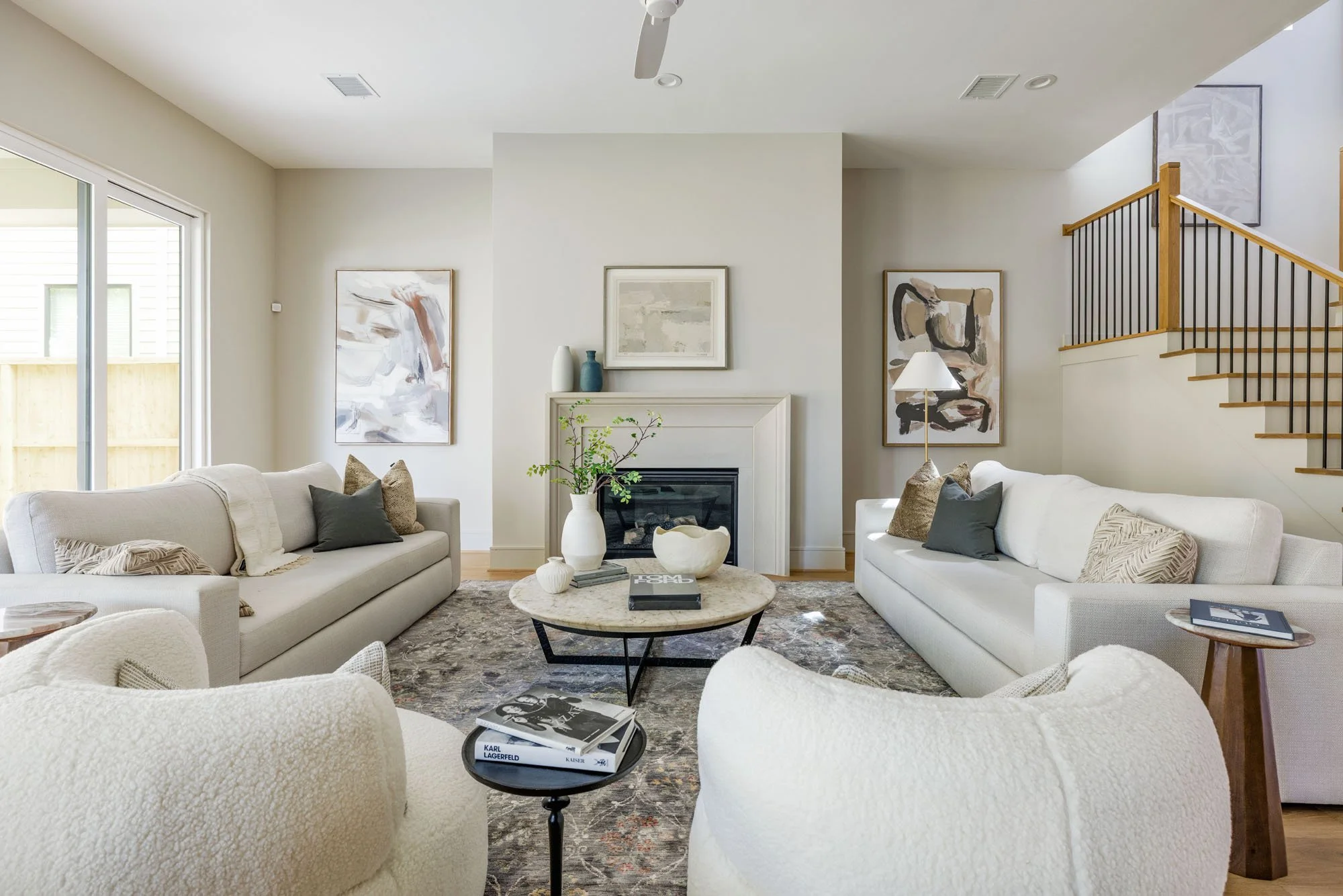 Symmetrical living room with cast stone fireplace, cream sofas, and marble coffee table