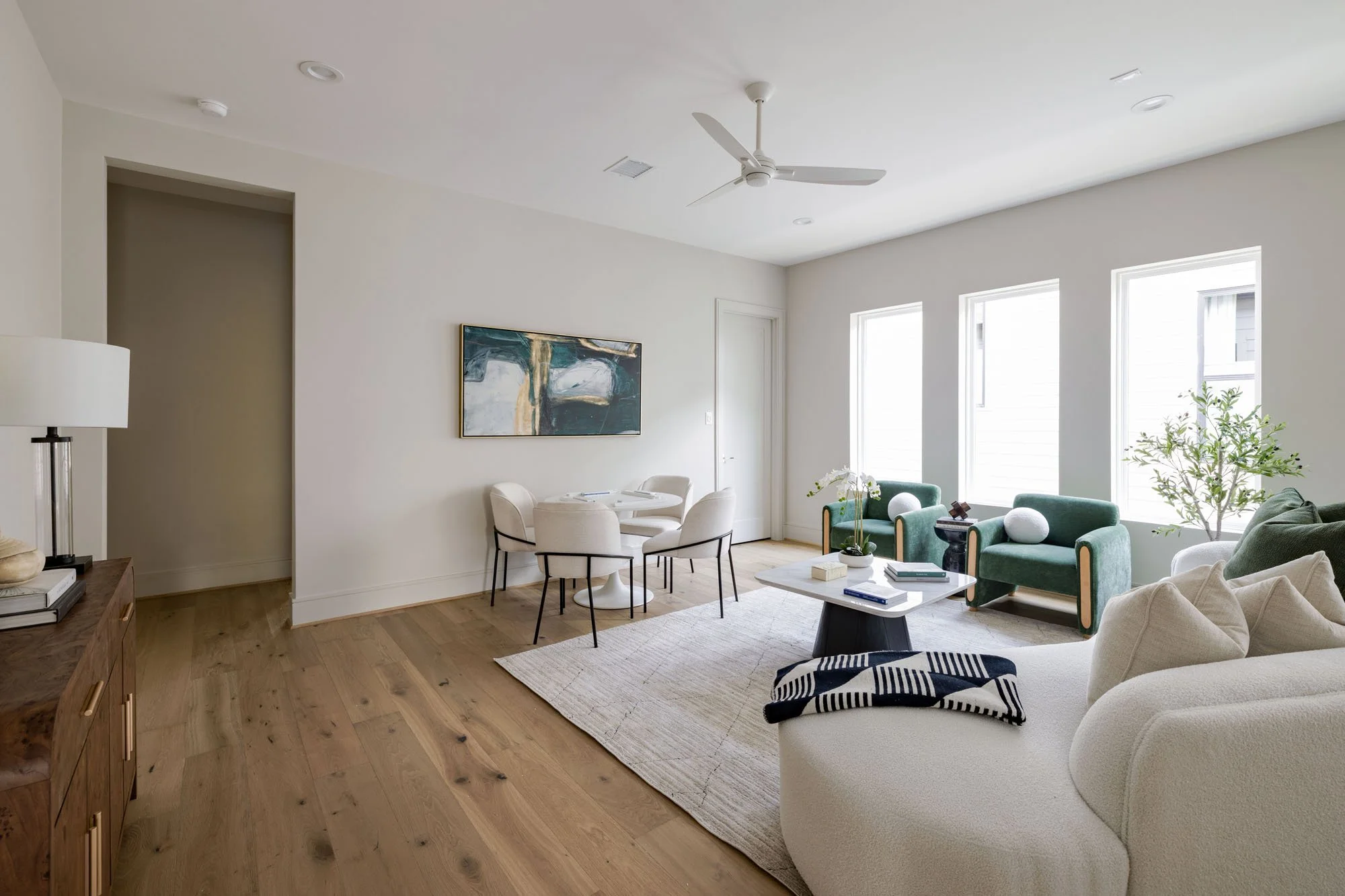 Upstairs game room with game table, green velvet chairs, white bouclé sofa, and wide-plank oak floors
