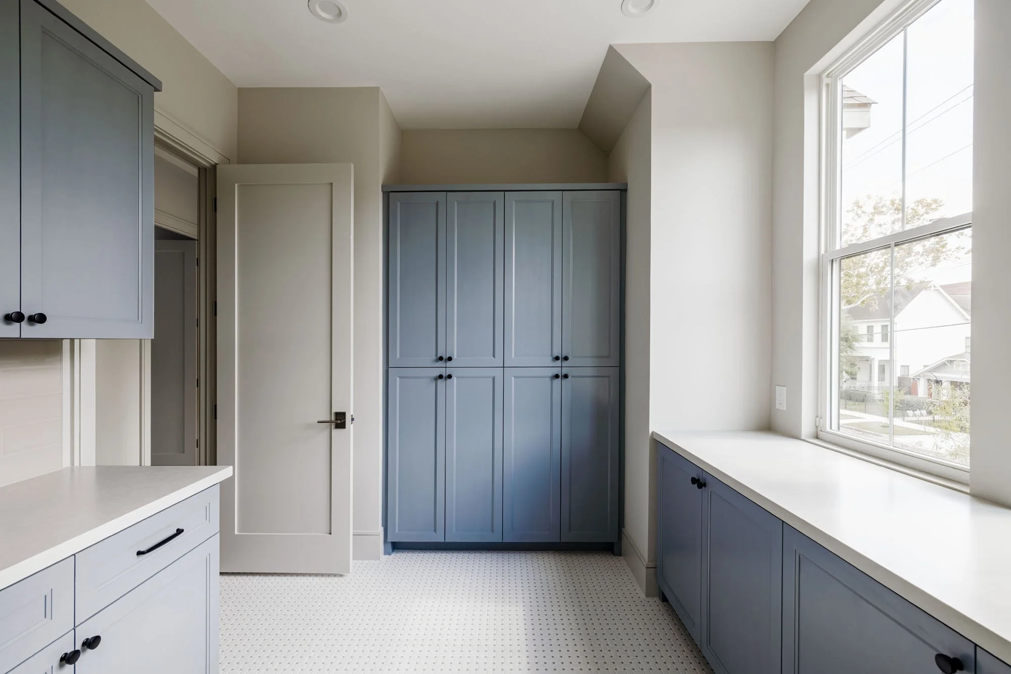Upstairs utility room with blue-gray shaker cabinets, basketweave tile floor, and long folding counter