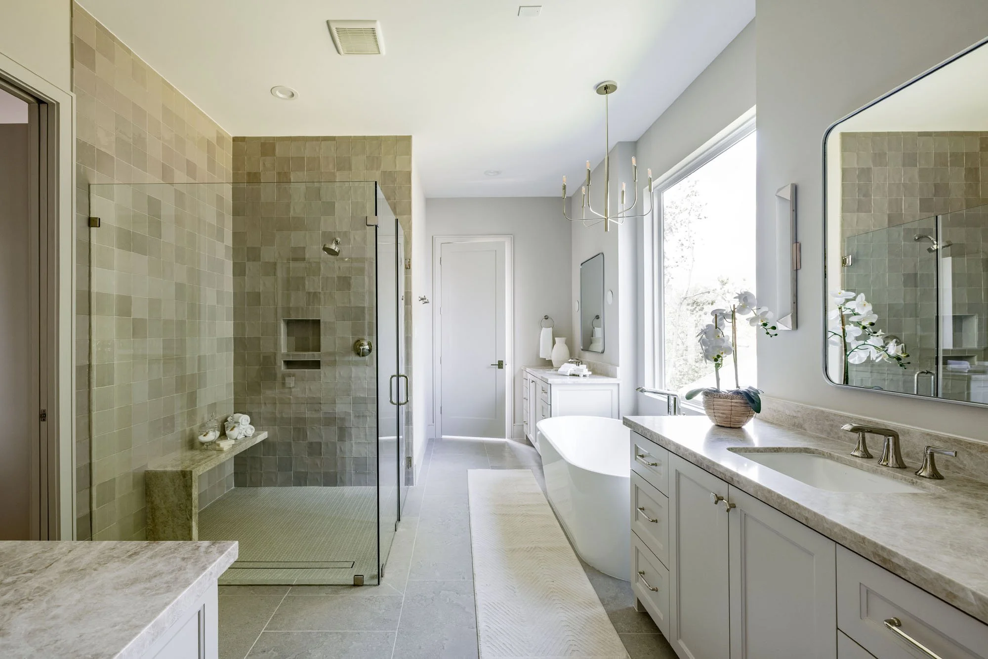 Primary bathroom with zellige tile walk-in shower, freestanding tub, and dual quartzite vanities