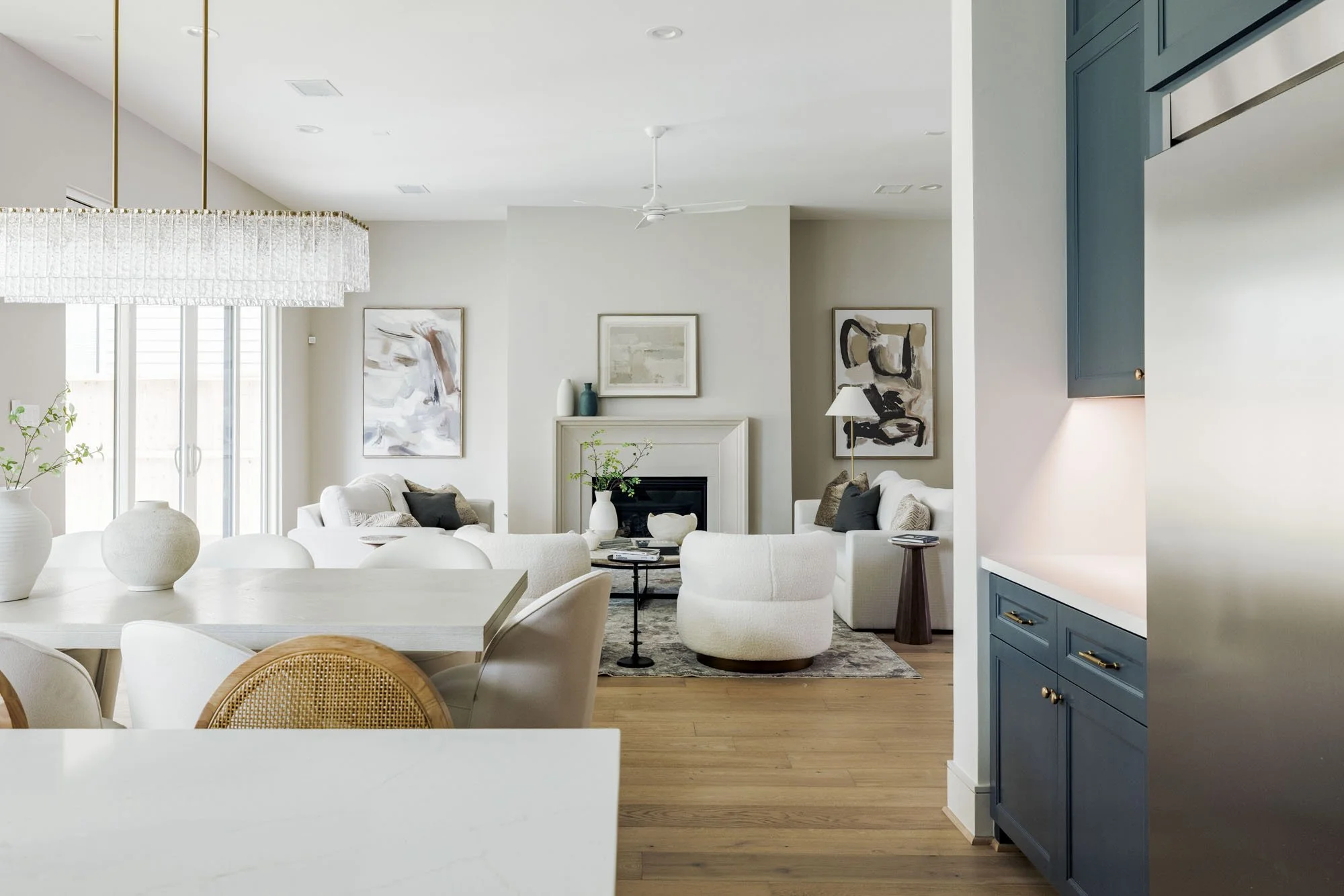 View from kitchen island to the living room with cast stone fireplace and white bouclé chairs