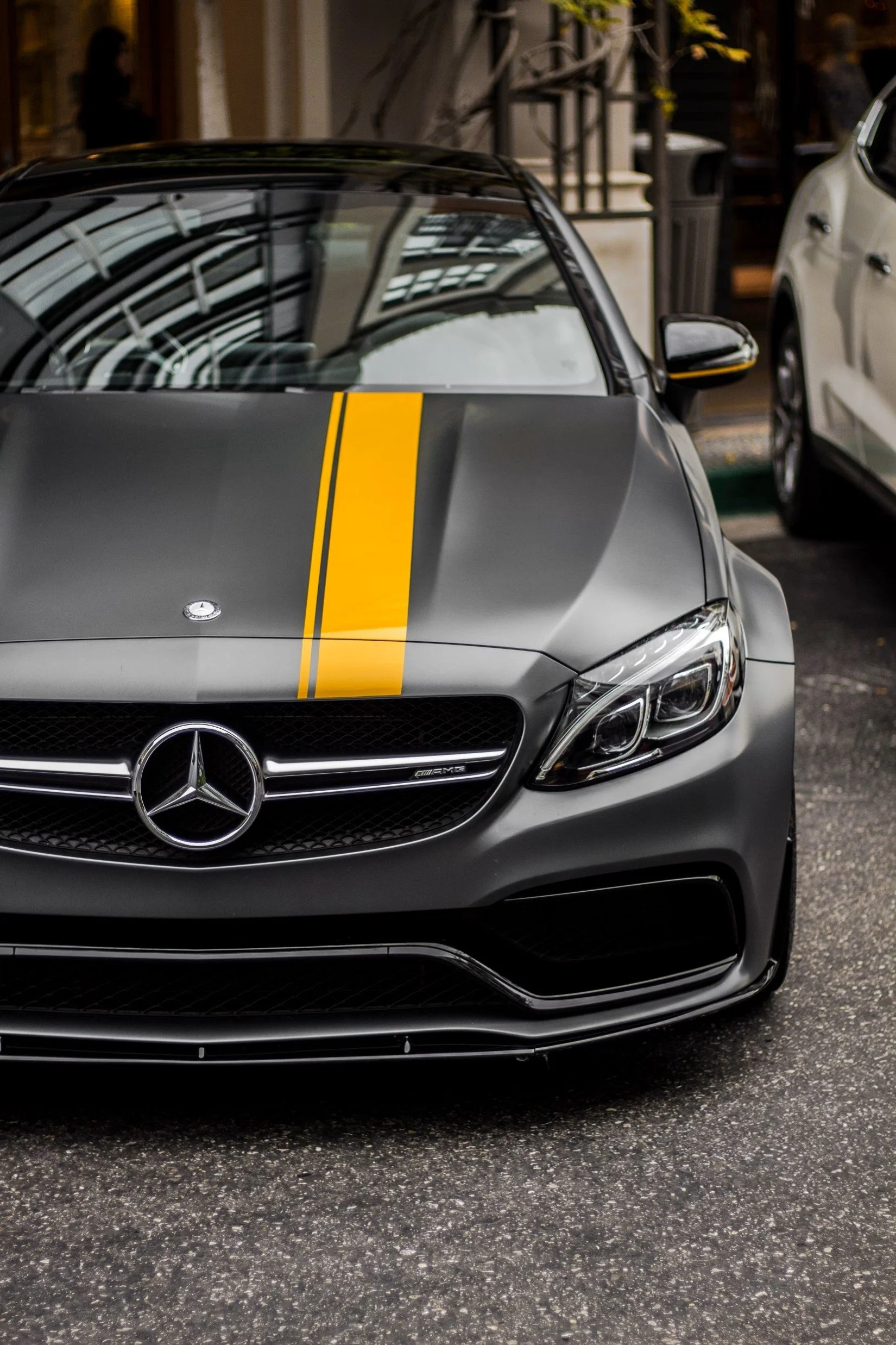 Matte black Mercedes-Benz sports car with yellow racing stripe parked outside.