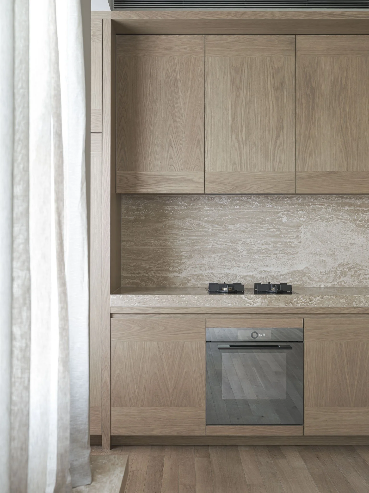 Modern kitchen with wooden cabinets, marble backsplash, and built-in oven.
