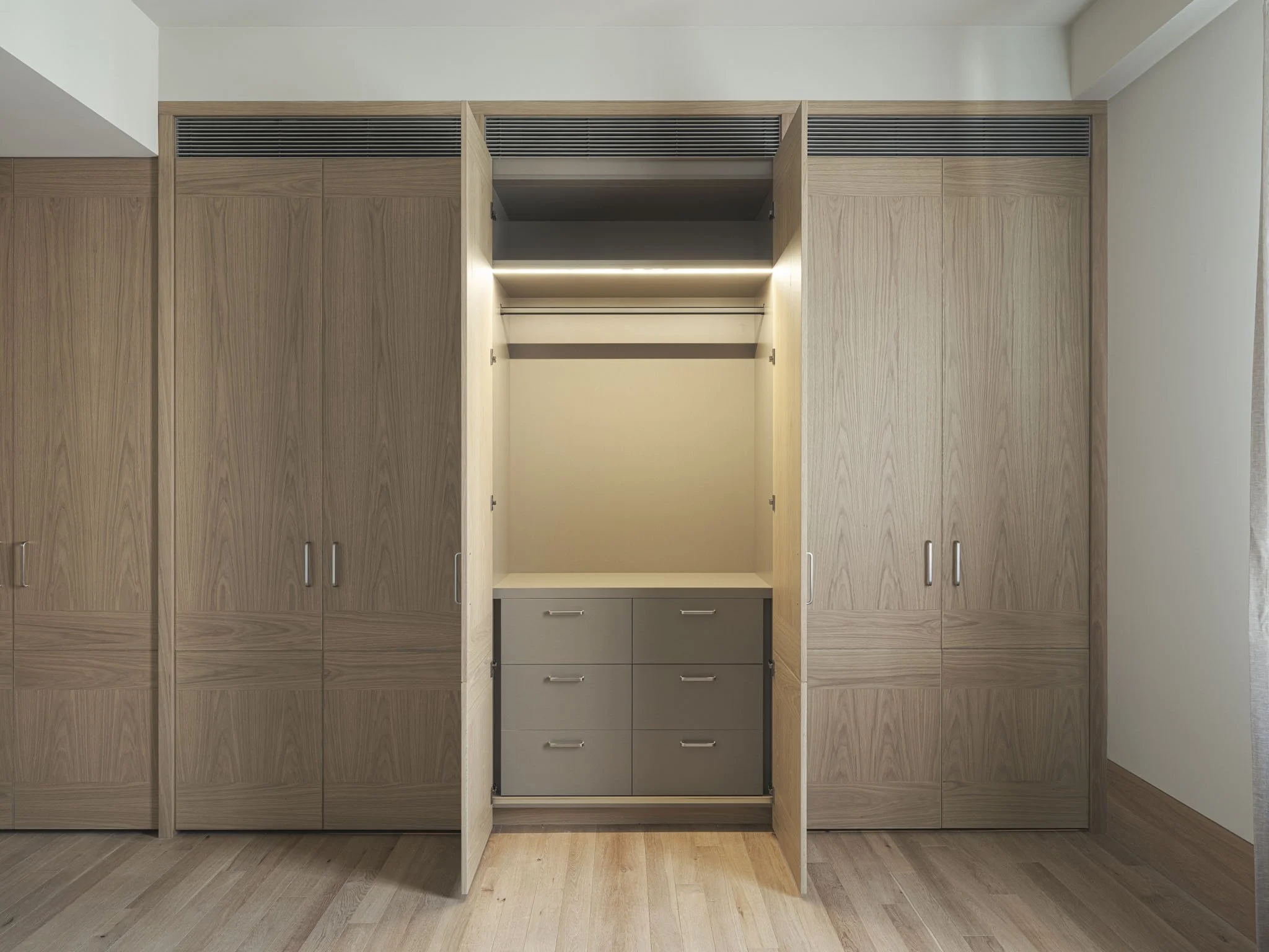 Open closet with drawers, shelves, and hanging space in a modern bedroom.