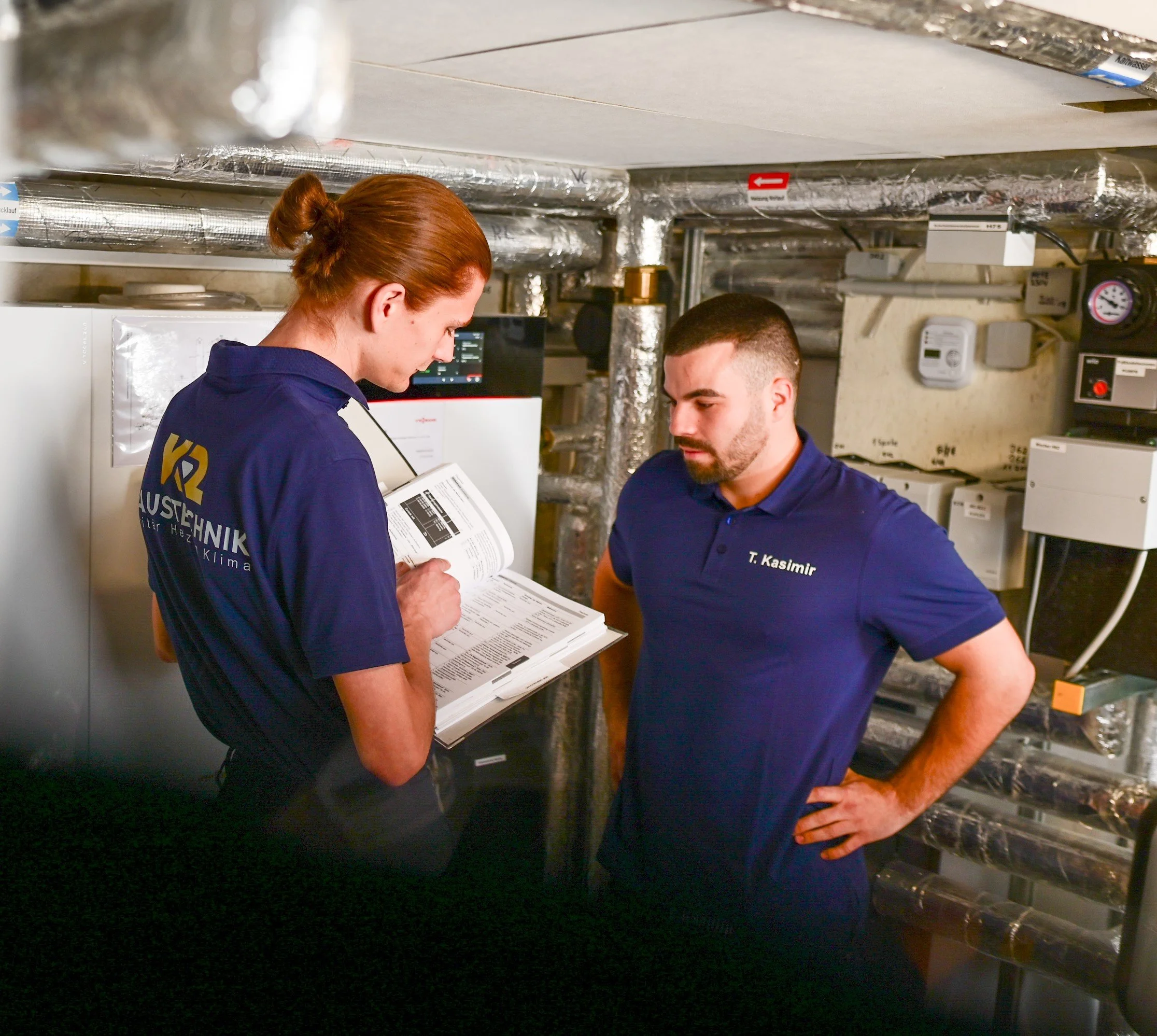 Zwei Techniker in einem Heizungsraum, die eine Checkliste durchgehen.