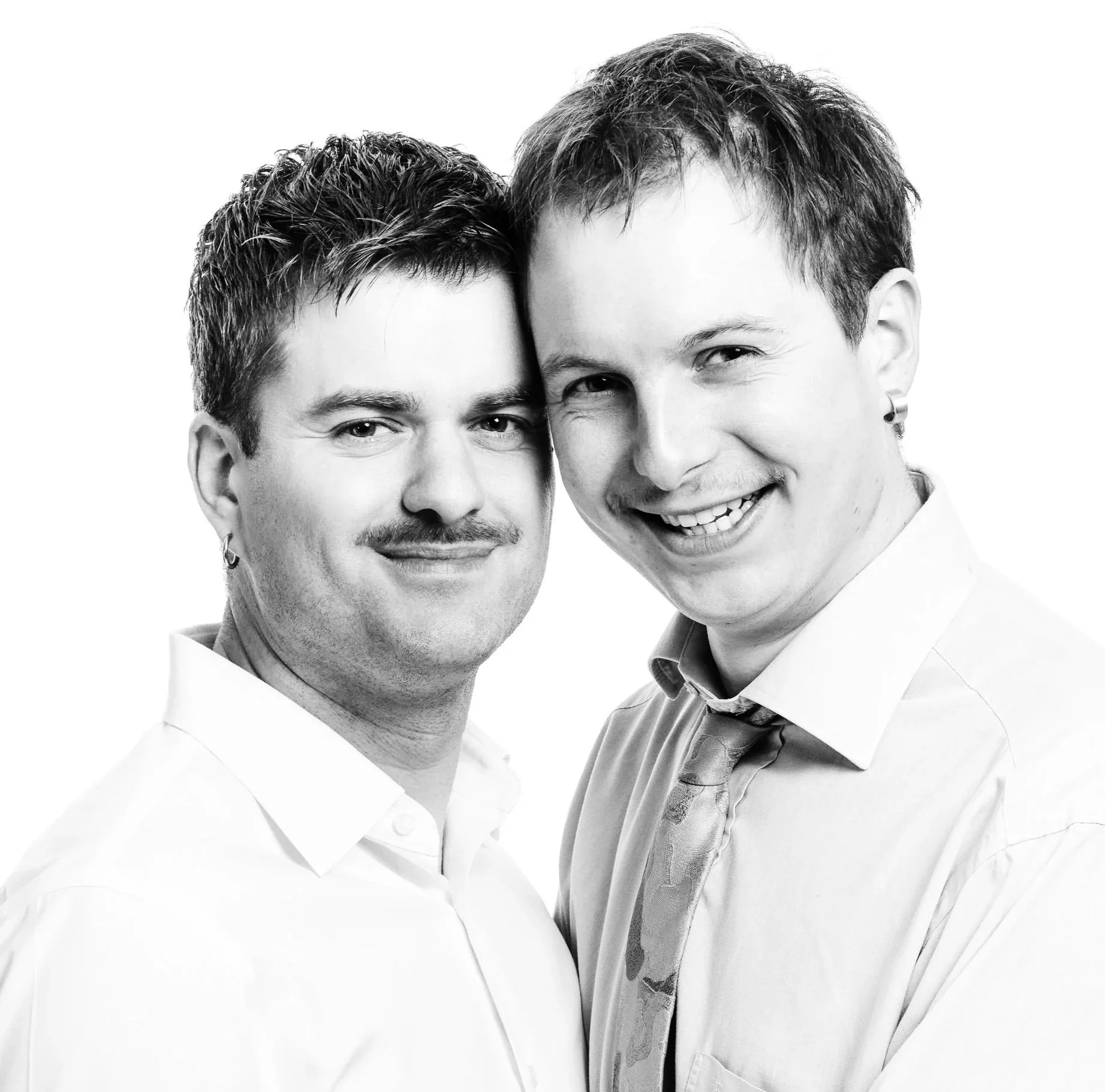 Two men standing close together, smiling and hugging each other, in black and white.