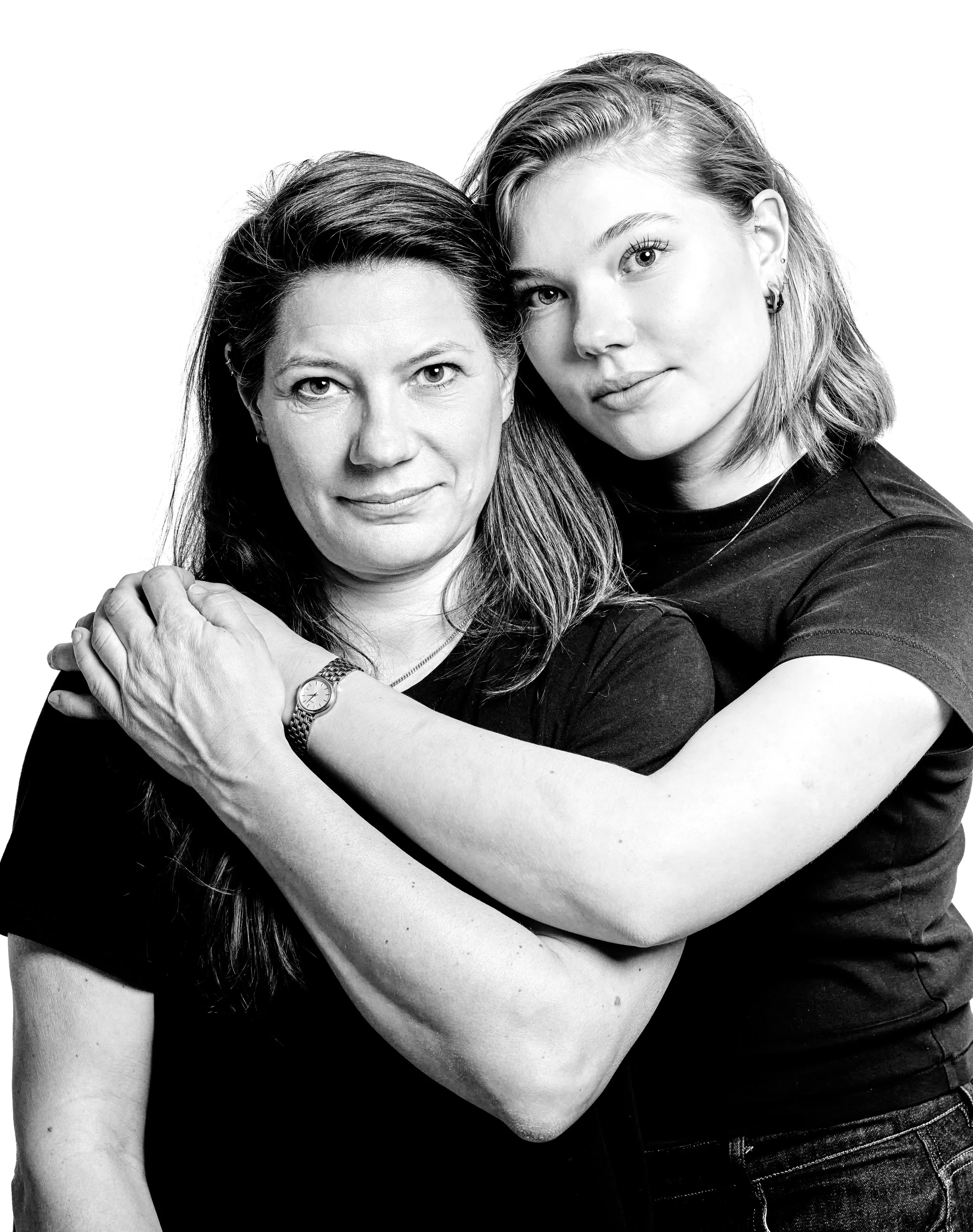 A black and white portrait of two women, one older and one younger, embracing each other and looking at the camera.