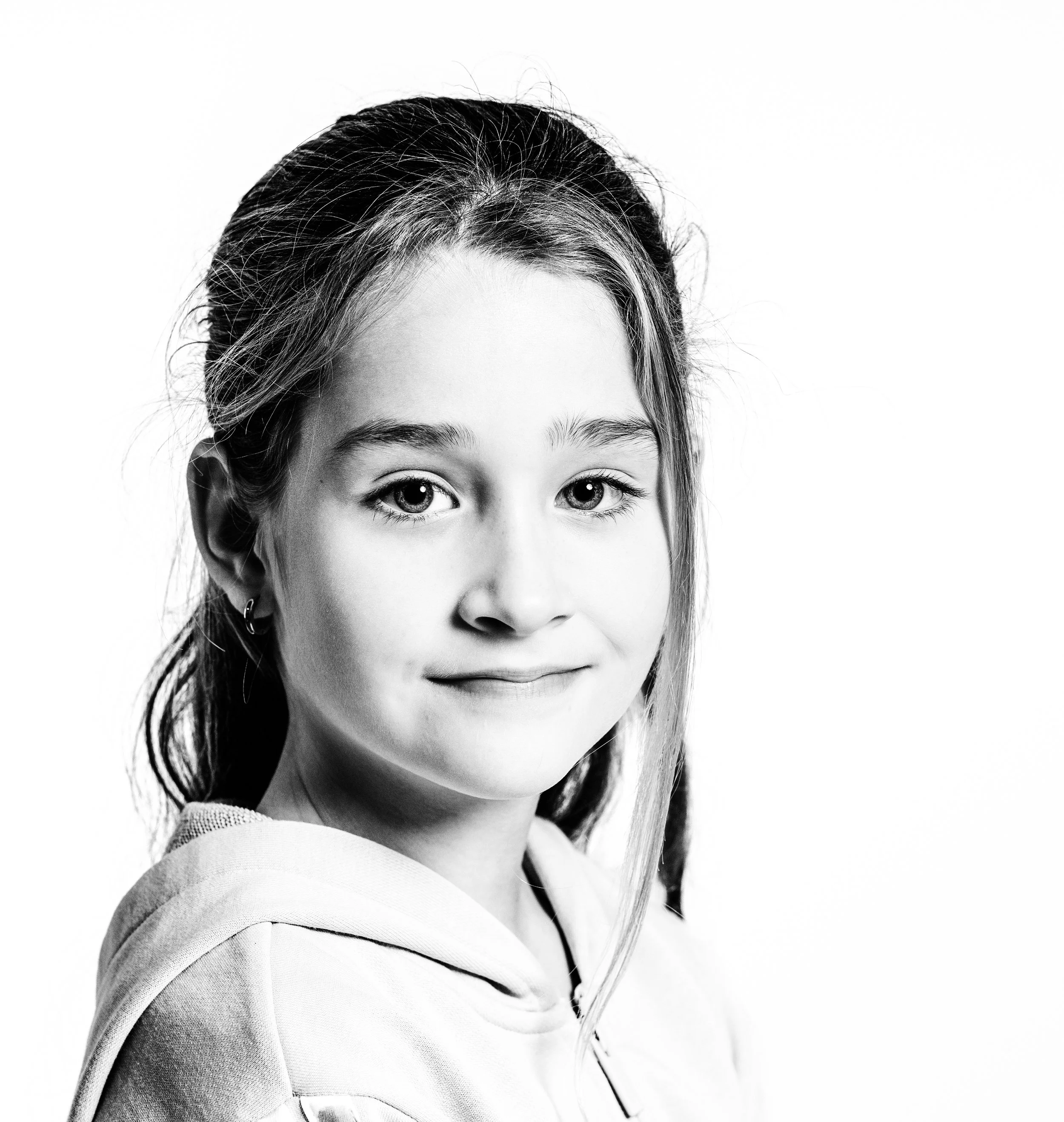 Black and white portrait of a young girl with long hair, wearing a hoodie.