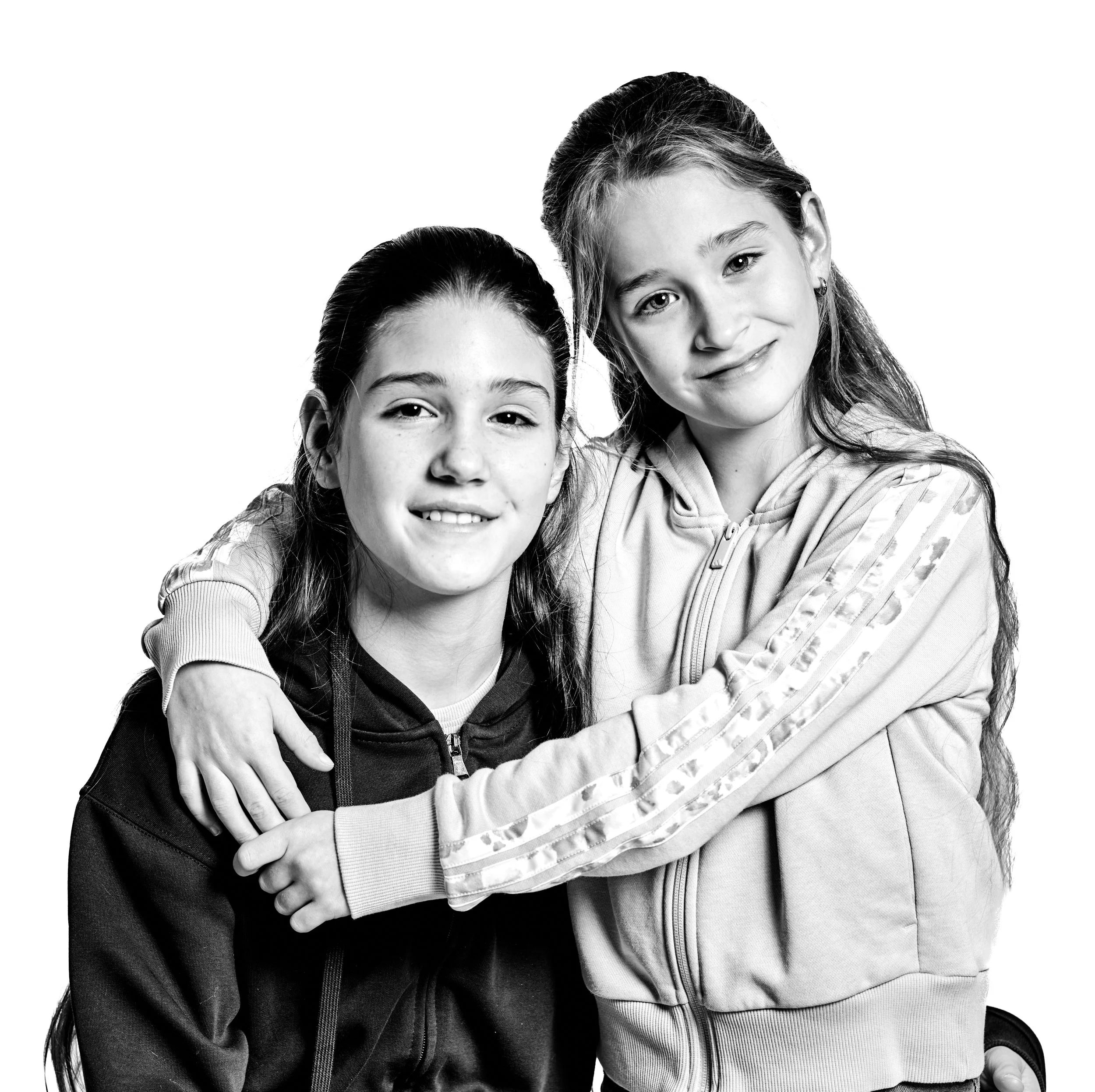 Black and white photo of two young girls with long hair smiling and hugging each other