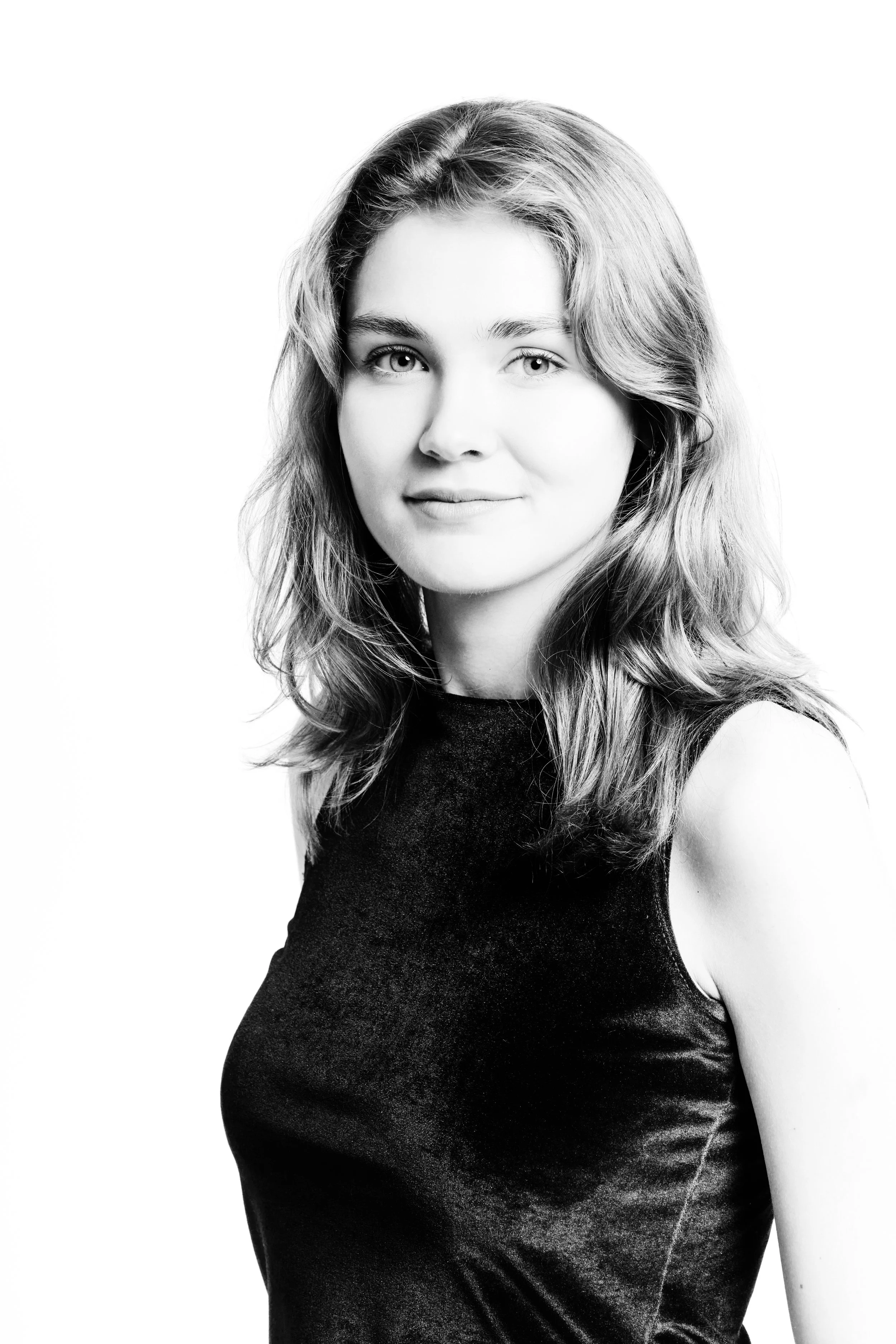Black and white portrait of a woman with shoulder-length wavy hair wearing a sleeveless top.