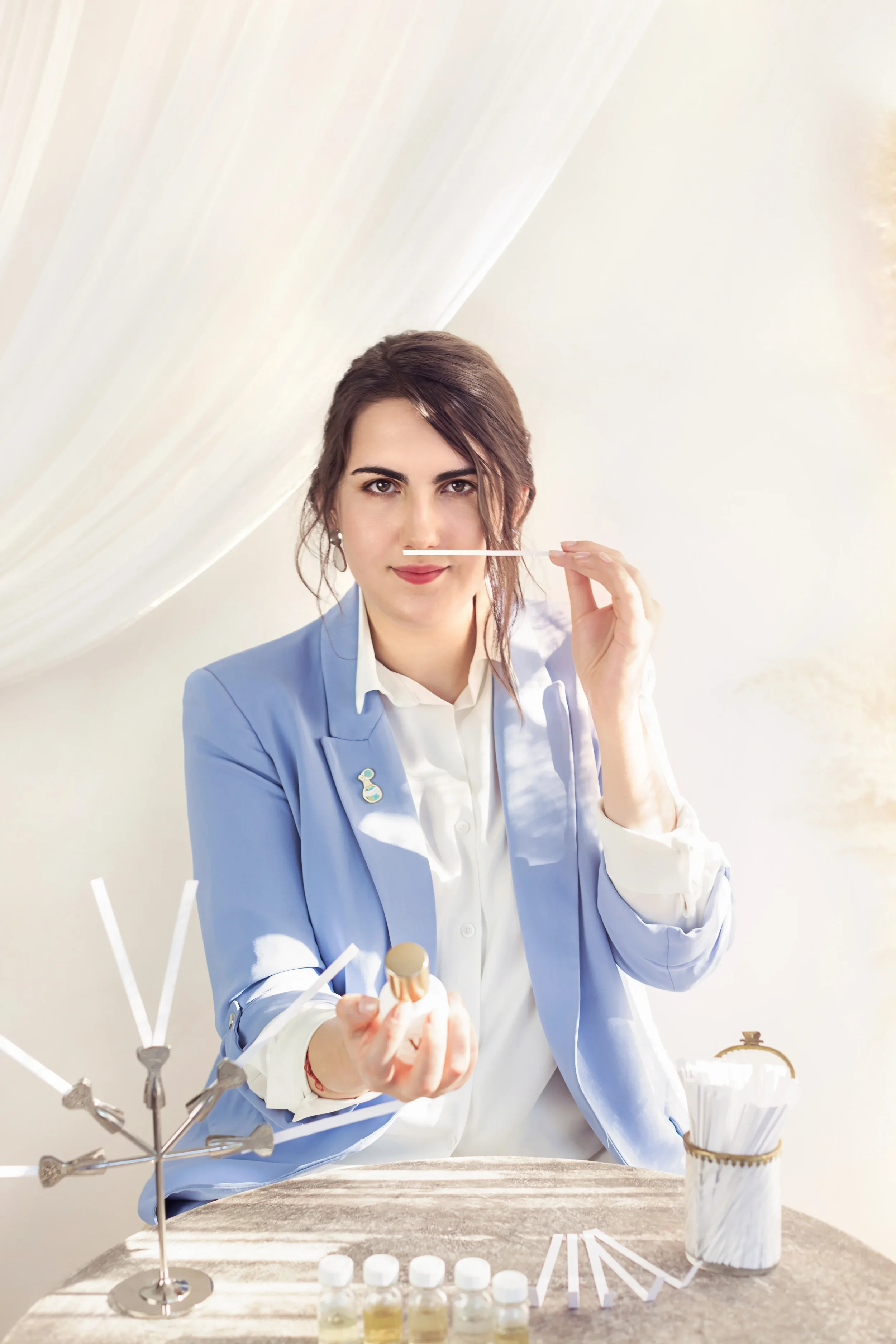 Perfumer Nyárádi Natália demonstrating the architectural process of fragrance creation with scent blotters and raw perfume ingredients.