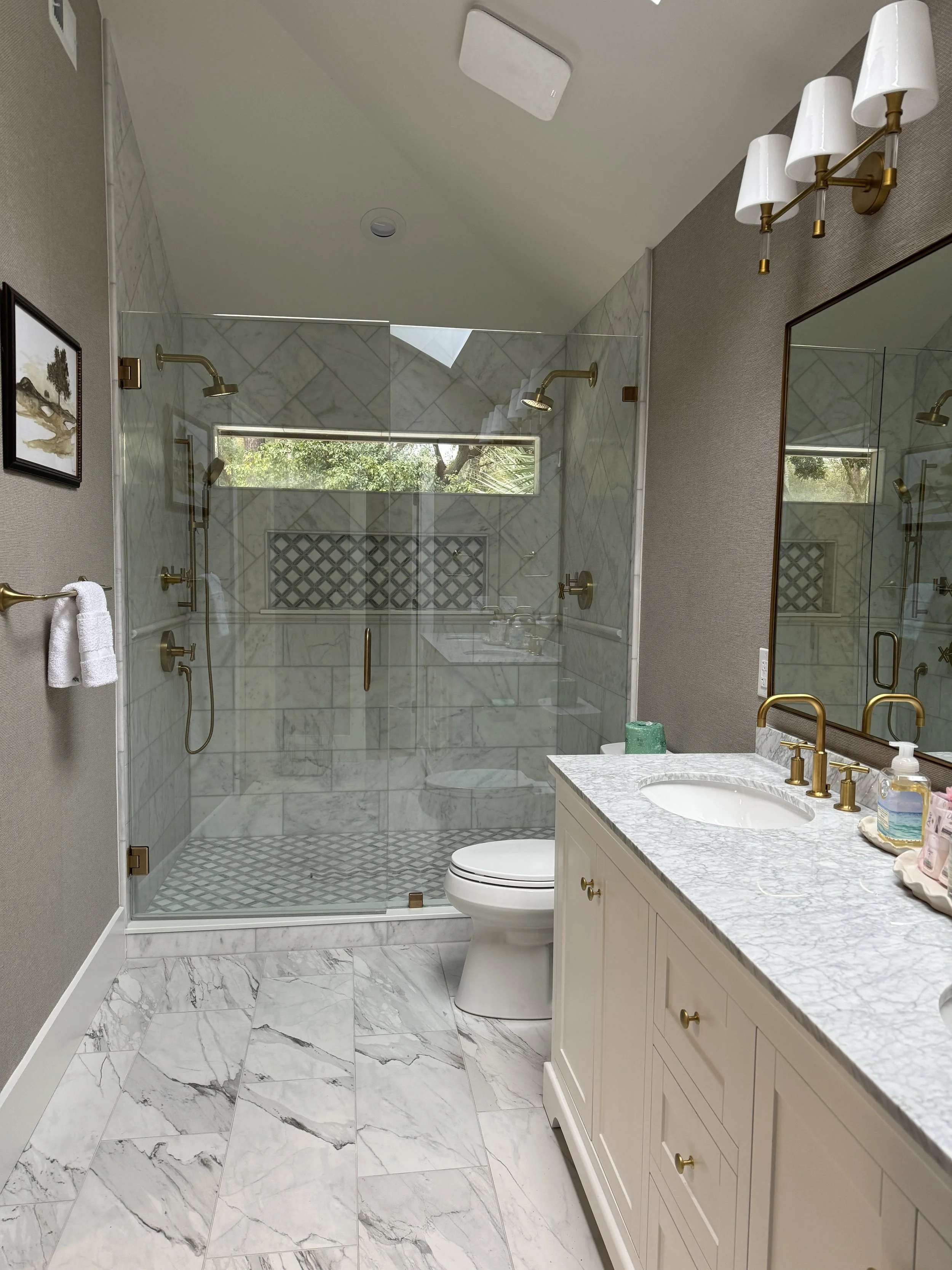 Modern kitchen with white cabinets, granite countertops, stainless steel appliances including a refrigerator, microwave, and oven, and a central island with a black faucet and sink. Two pendant lights hang above the island, and hardwood floors complete the space.