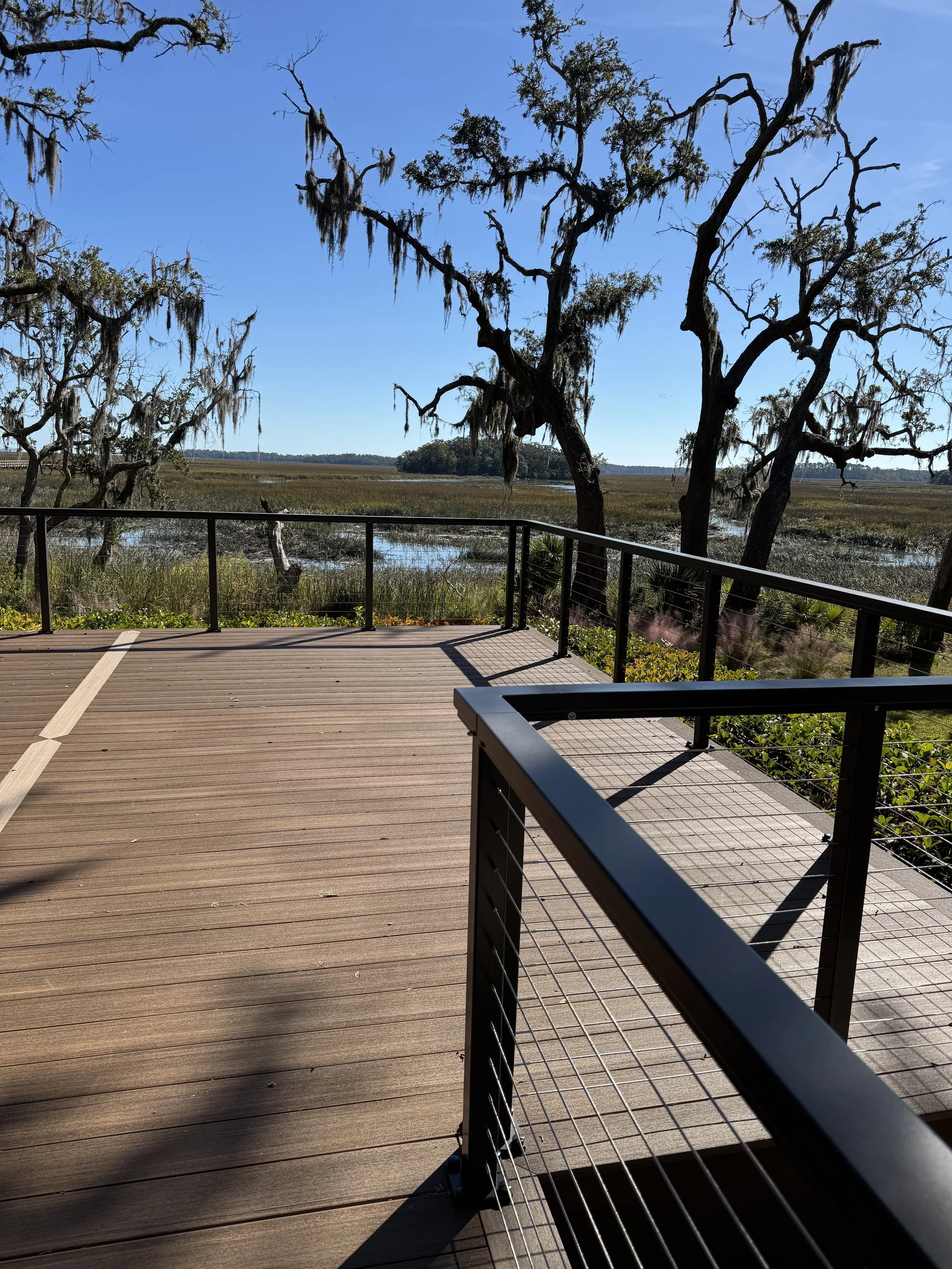 Person pressure washing a brick driveway near a car and a stone wall.