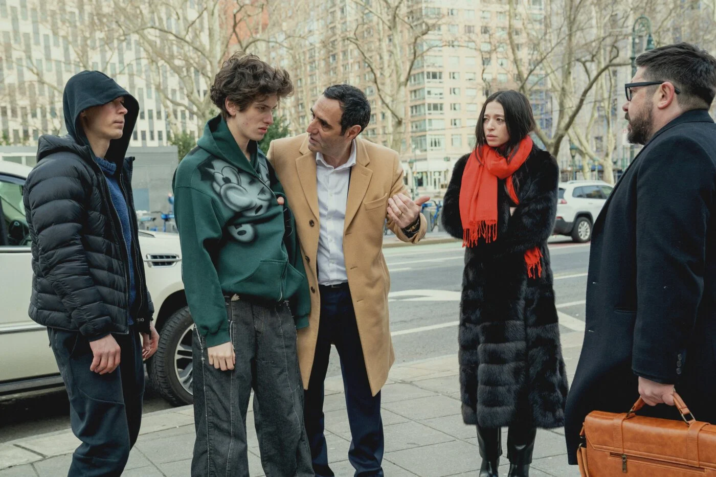 Ivan, Ani, and the adults arguing on a city street in Anora, all looking tense and exhausted during the film’s escalating conflict.