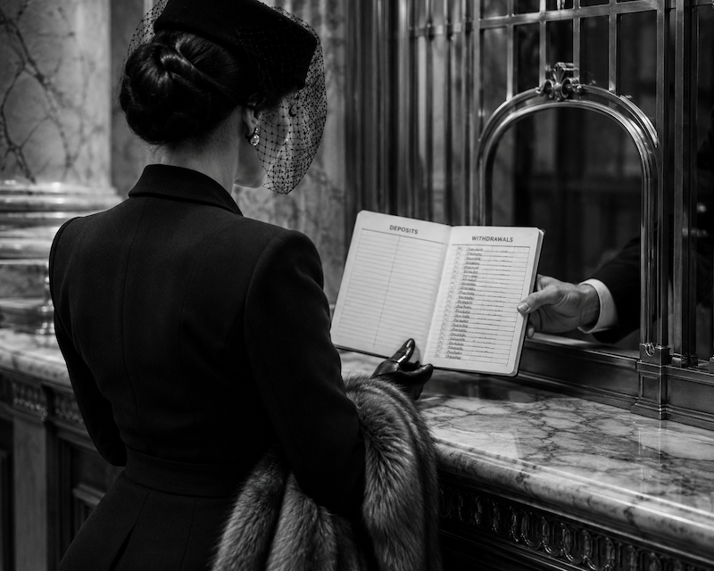 An elegantly dressed woman in a vintage bank studies a passbook showing pages of withdrawals and no deposits, symbolising a one-sided relationship and emotional imbalance.