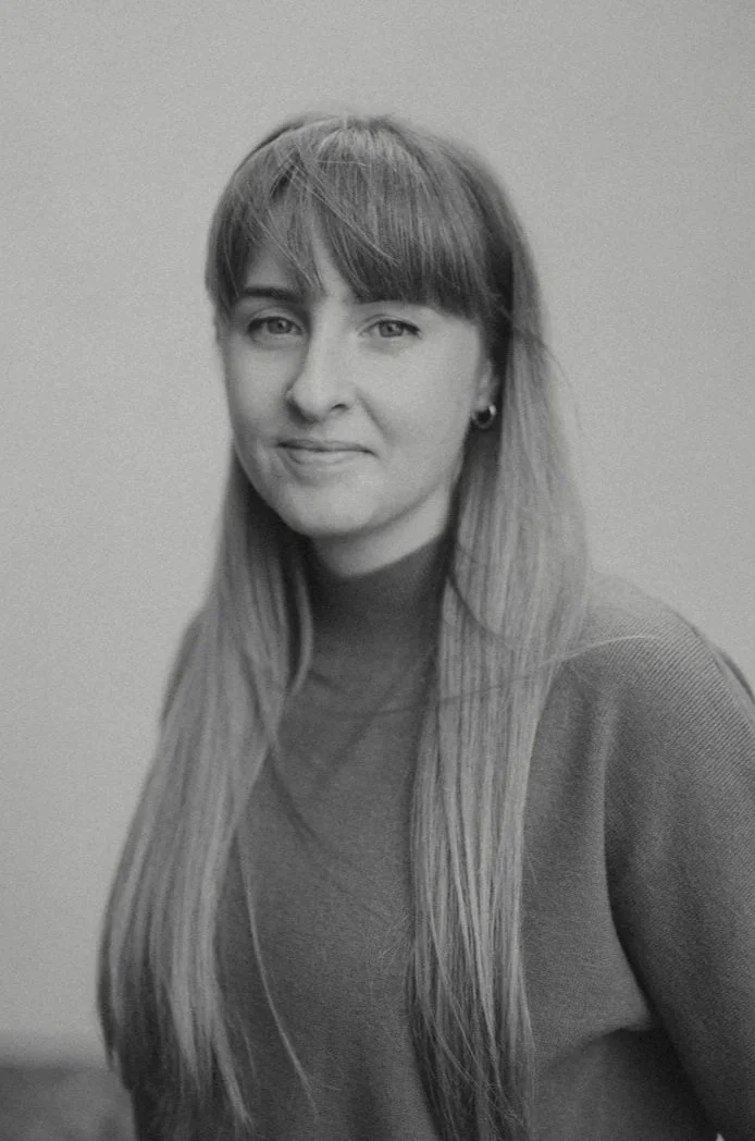 Black and white portrait of a woman with shoulder-length hair, wearing a turtleneck sweater, smiling slightly, against a plain background.