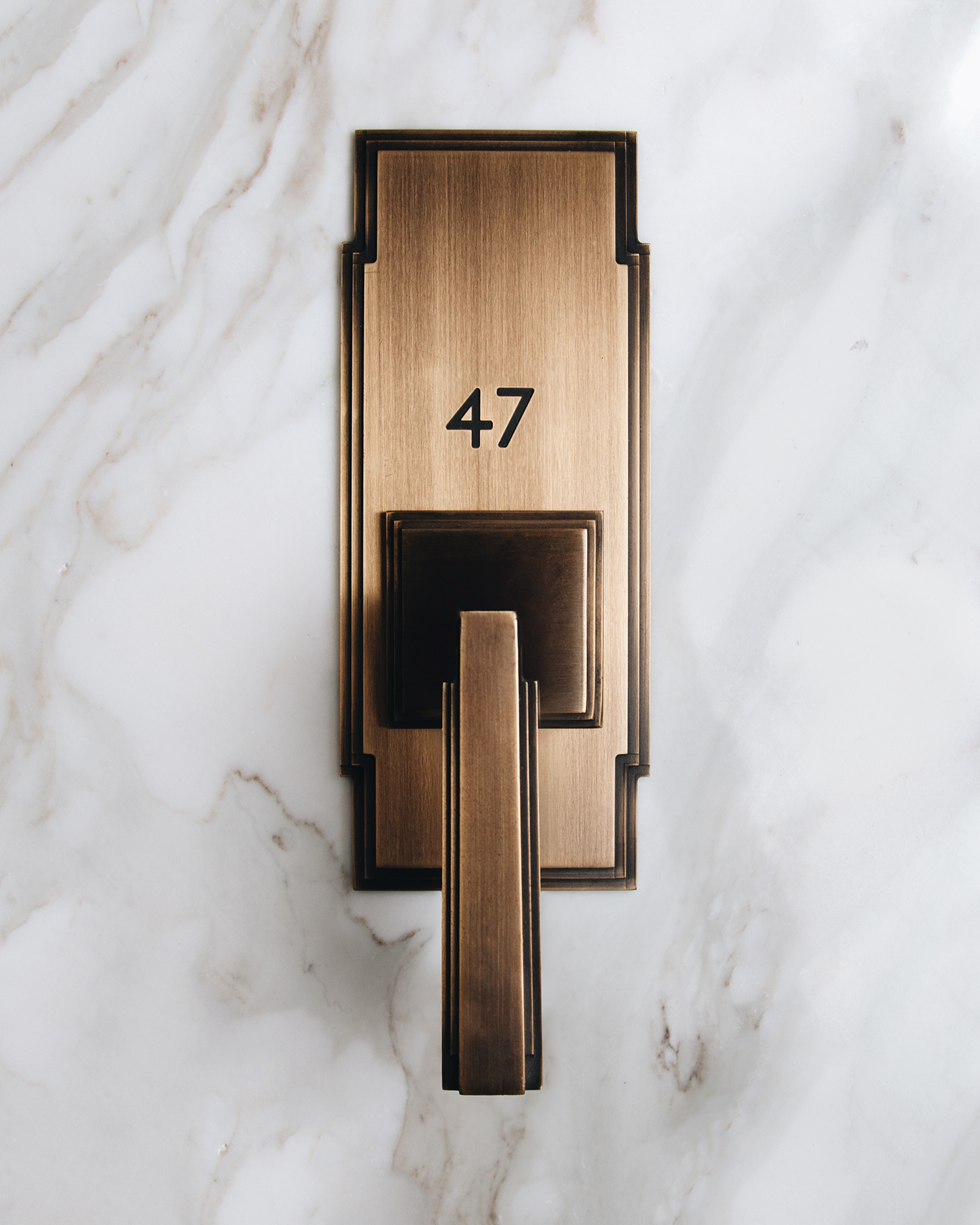 art deco lever and escutcheon plate in satin brass and black with etched details.