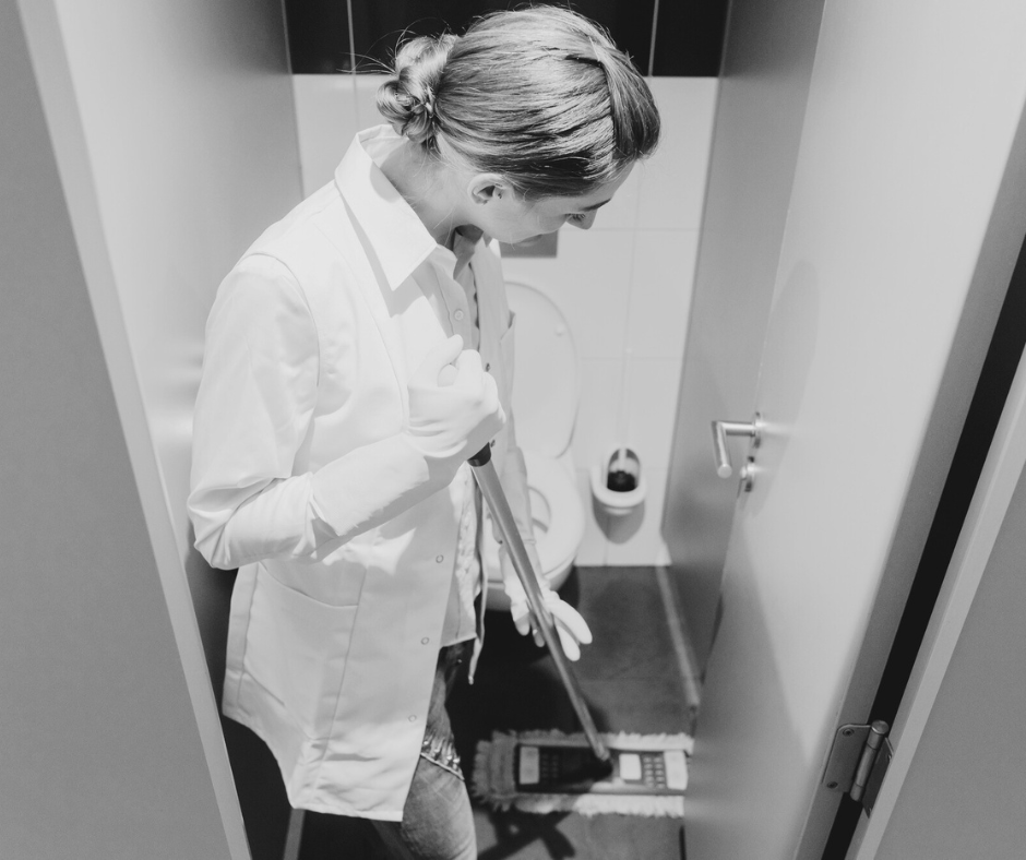 Custodian cleaning a restroom with professional tools, highlighting commercial deep cleaning and janitorial services that ensure hygiene in business facilities.
