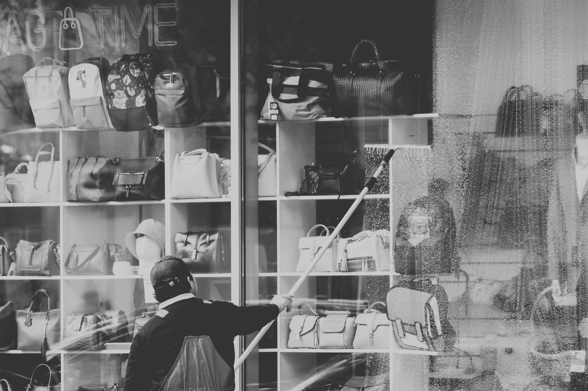 Commercial exterior maintenance crew cleaning storefront windows to prevent buildup and protect building appearance