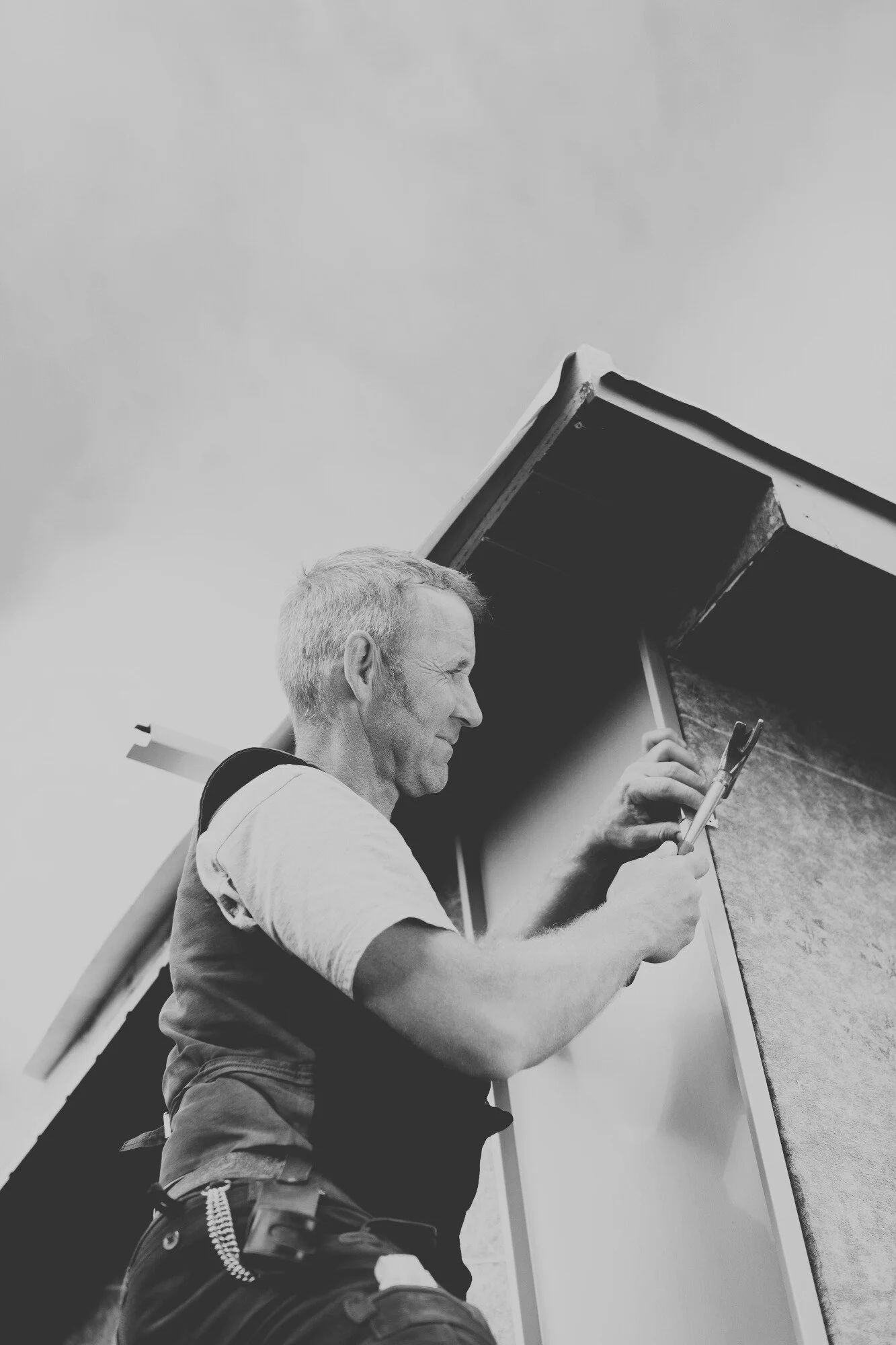 Exterior building maintenance technician repairing siding and trim to prevent long-term structural damage