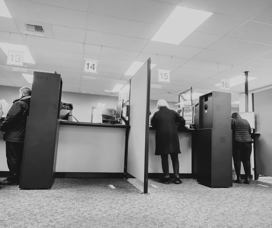 People standing at service counters inside a government office, representing professional janitorial services that keep municipal and public facilities clean and organized.