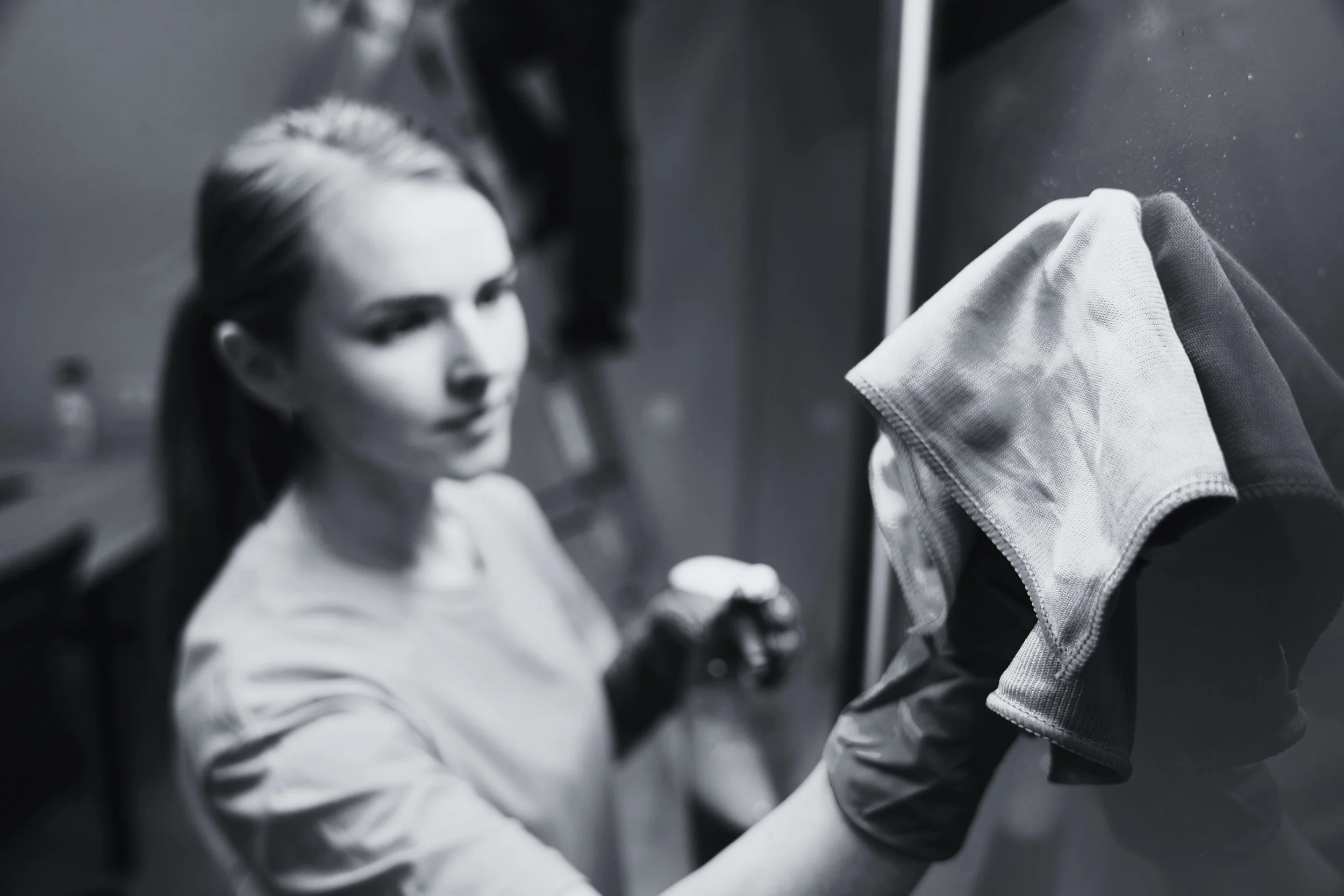 Professional janitorial services technician wiping interior glass during commercial cleaning quality inspection