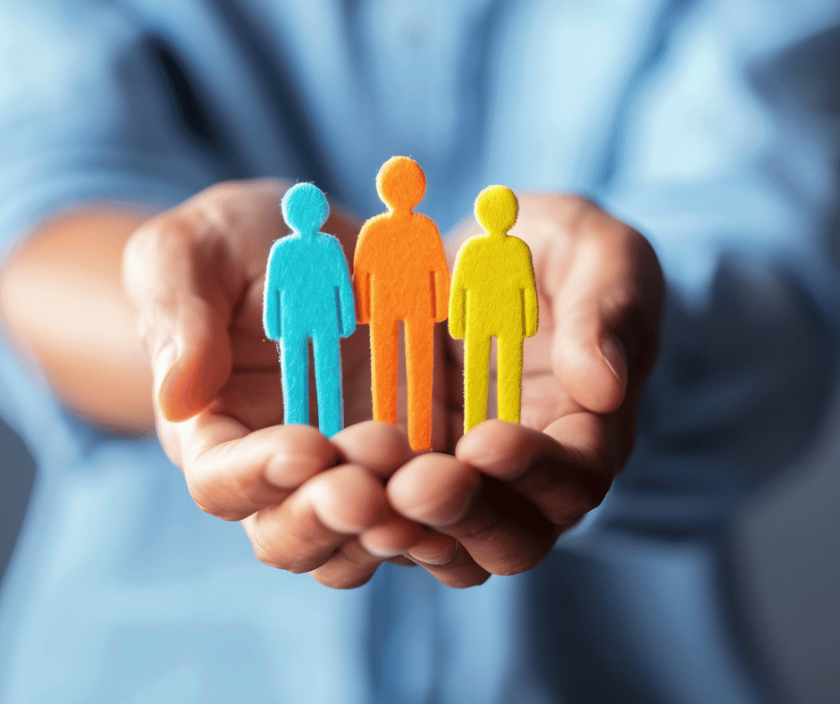 Mani che tengono tre sagome colorate di persone, simbolo di gestione e selezione del personale nelle risorse umane.
