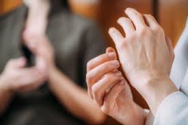 Close-up of a person using hands for EFT tapping, with another person blurred in the background.