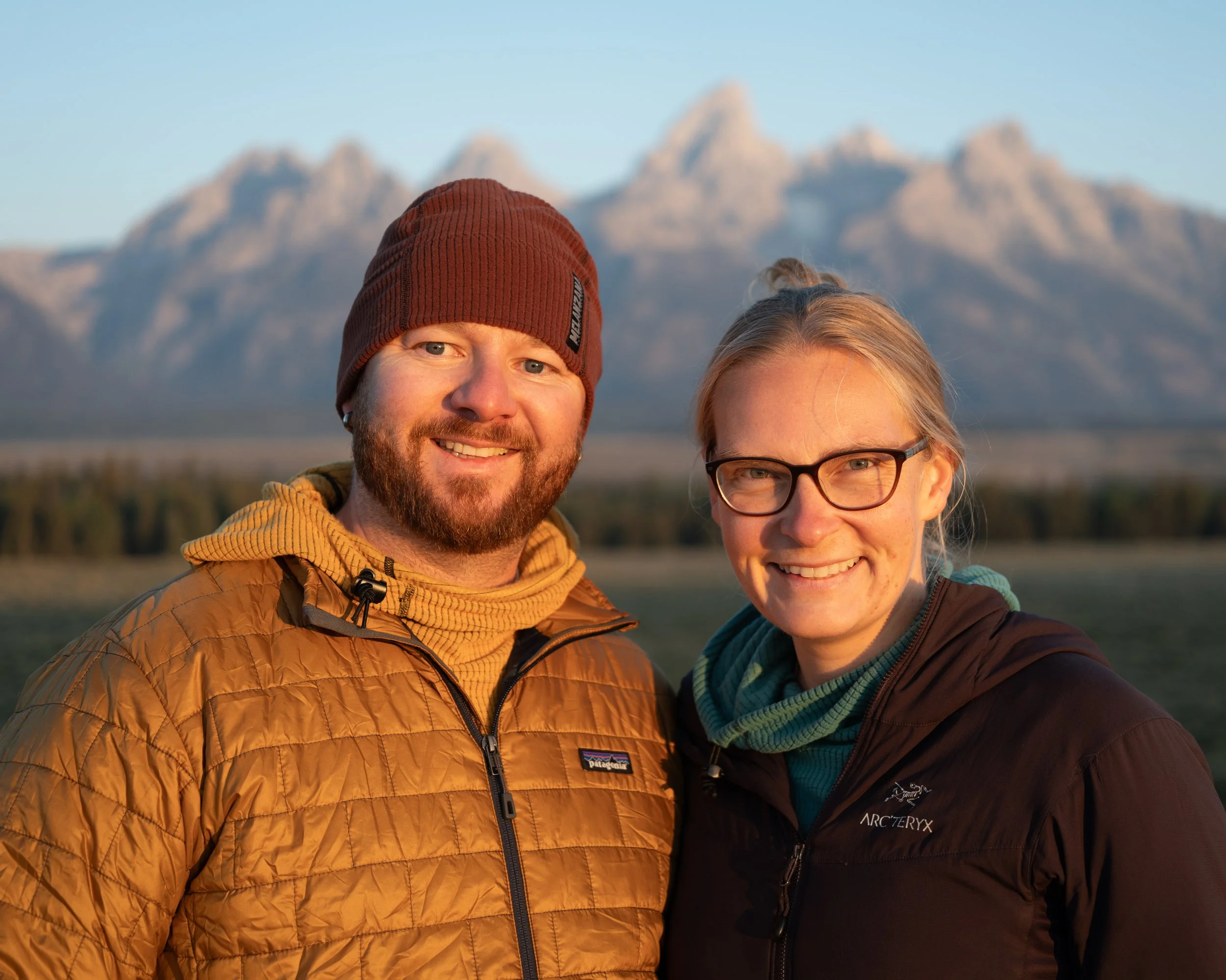 Two people smiling outdoors with a mountain range in the background
