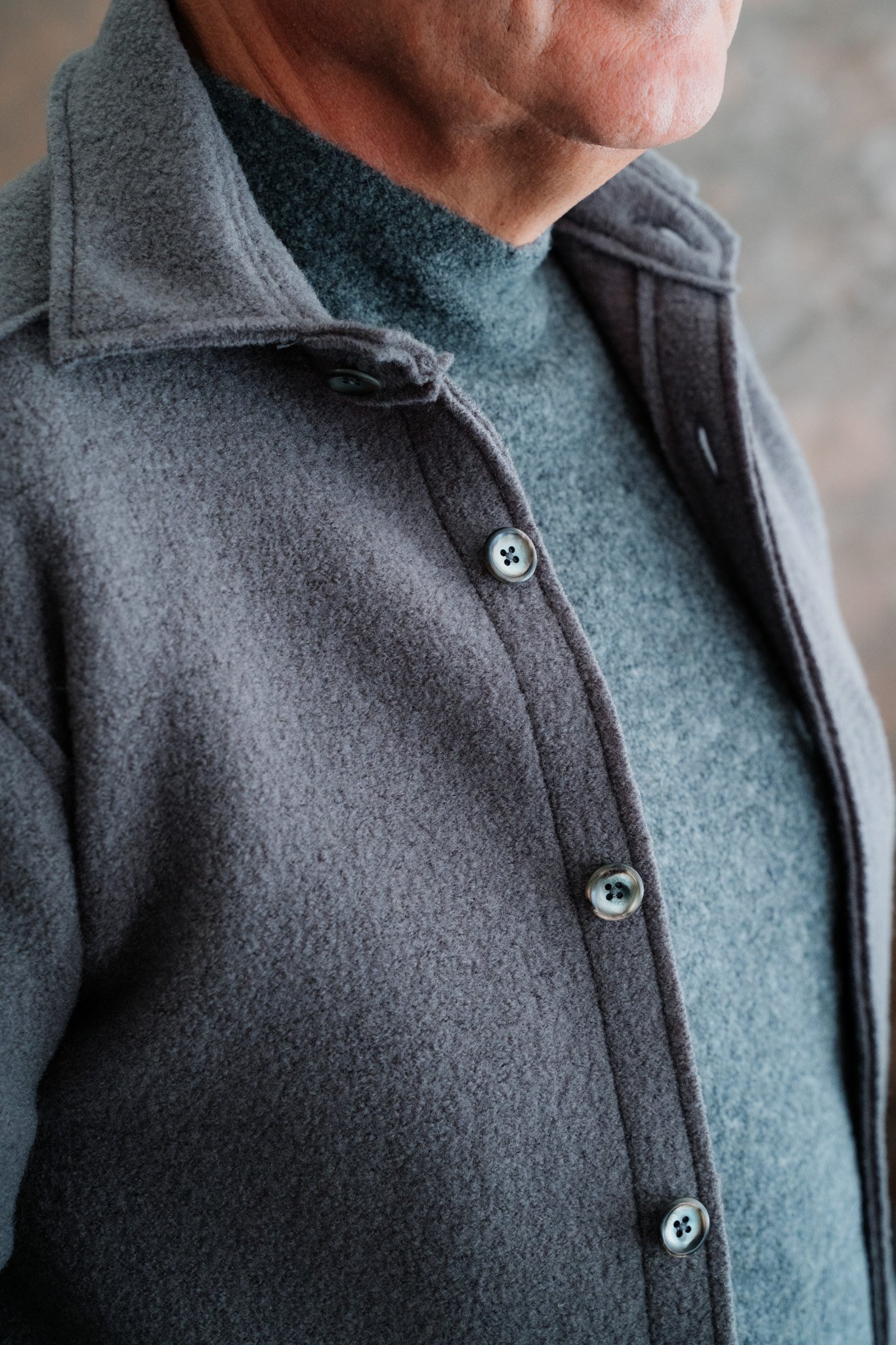 Nahaufnahme eines Mannes in grauer Jacke und grauem Pullover.