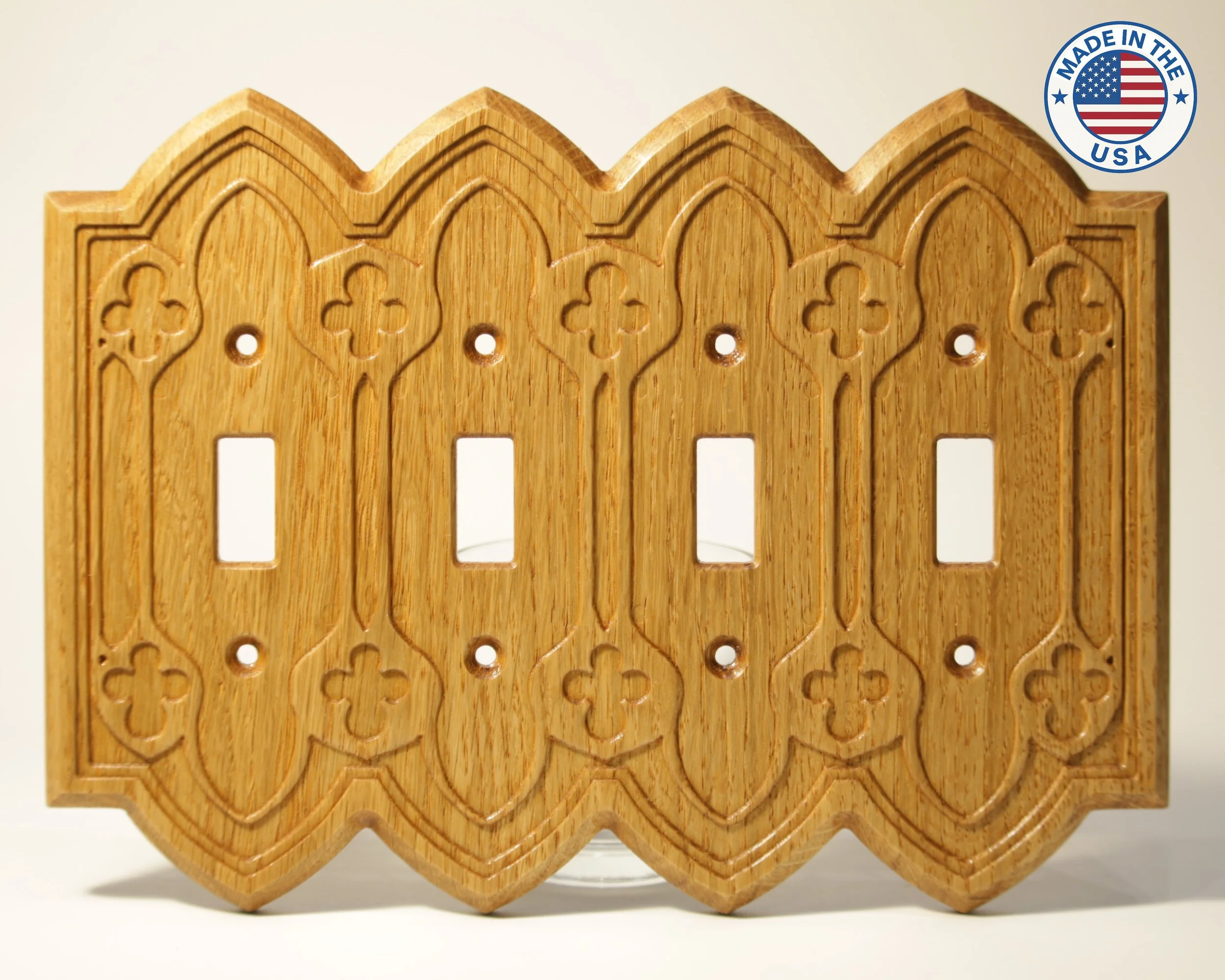 A wooden decorative piece with a series of intricate cut-out patterns and a zigzag top edge, featuring a circular sticker that says "Made in the USA" with an American flag design.