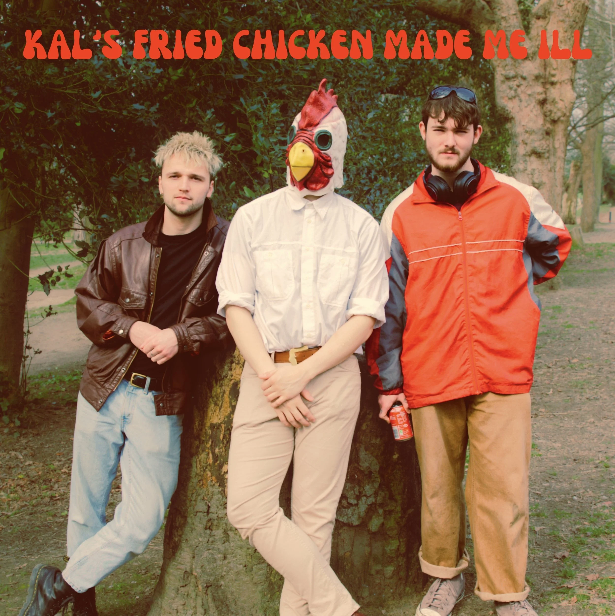 Three young men standing outdoors with trees in the background. The middle person wears a chicken mask and beige pants, while the other two wear casual jackets and pants. The top of the image has text in red that reads "KAL'S FRIED CHICKEN MADE ME ILL."