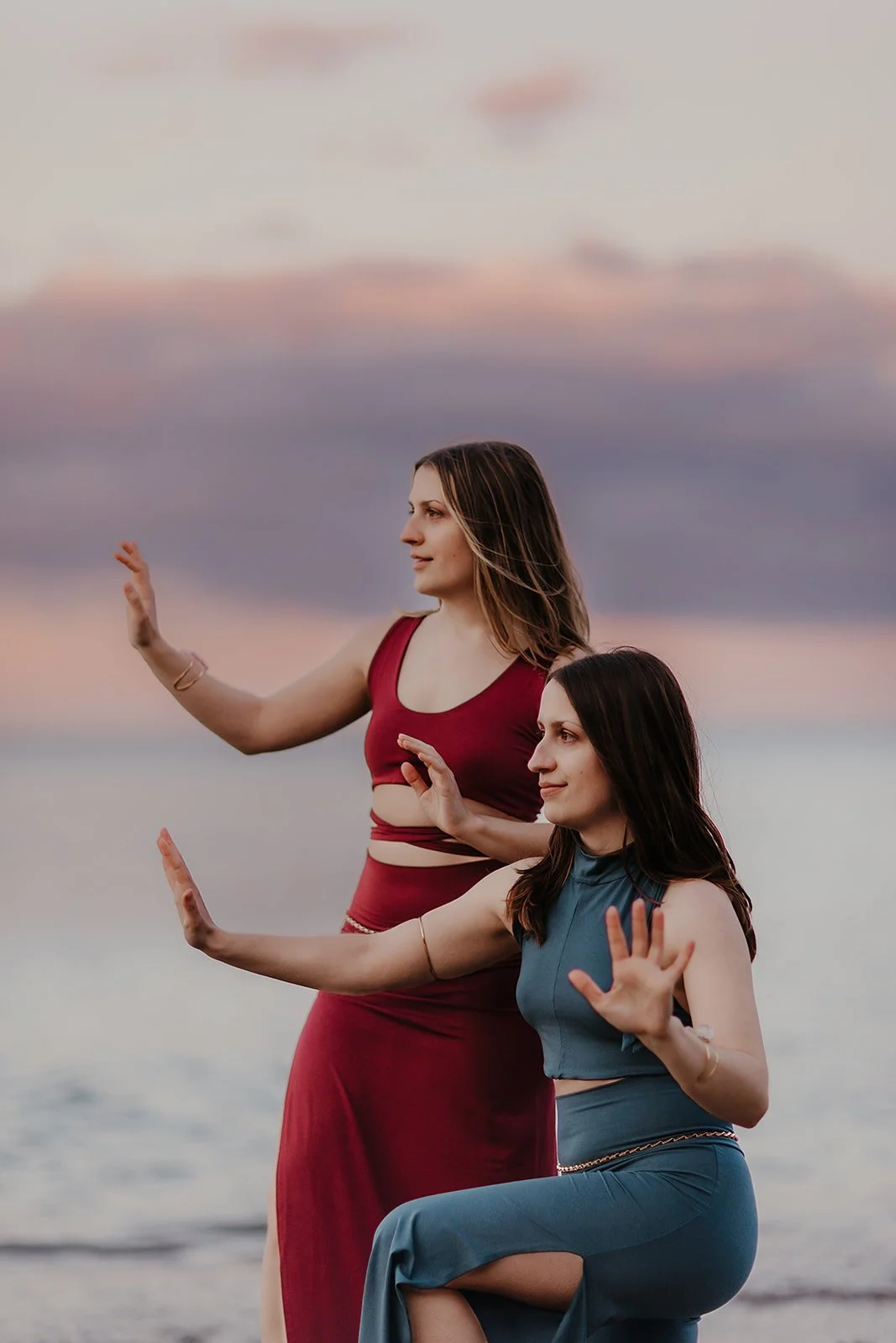 Lacey stand with her palms outward. Marley kneels with her palms outward.