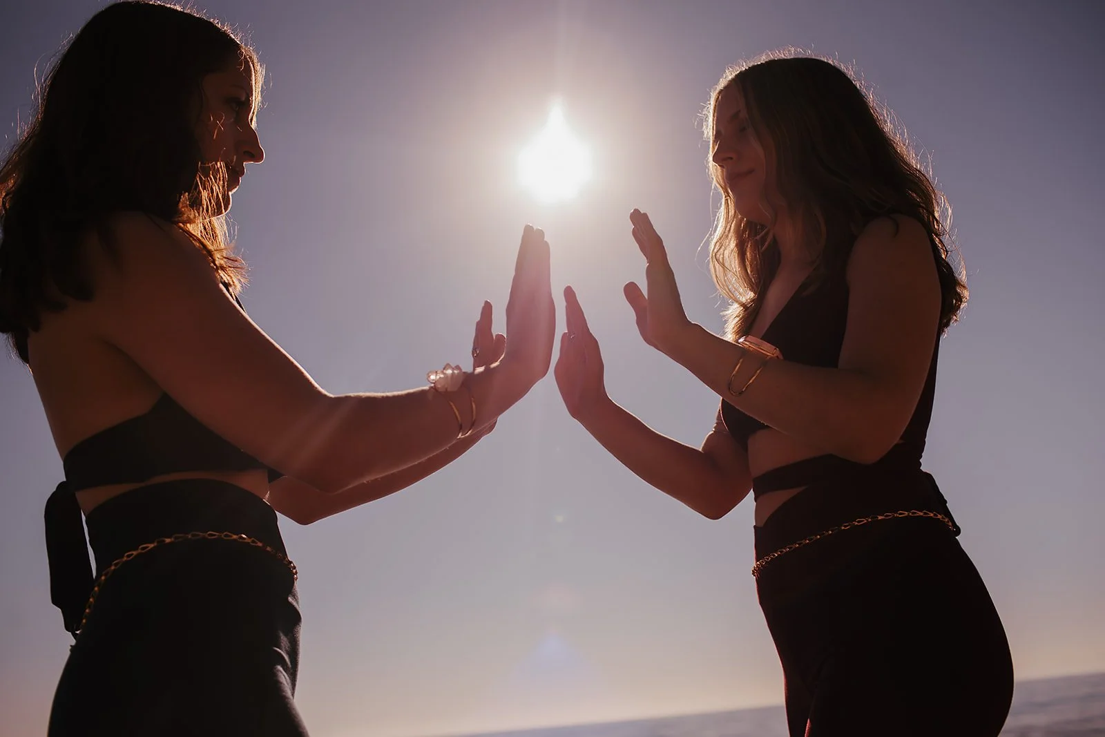 Marley and Lacey connect hands with the Sun above them.