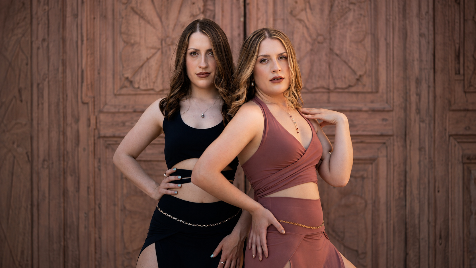 Marley and Lacey stand in front of a wooden door.