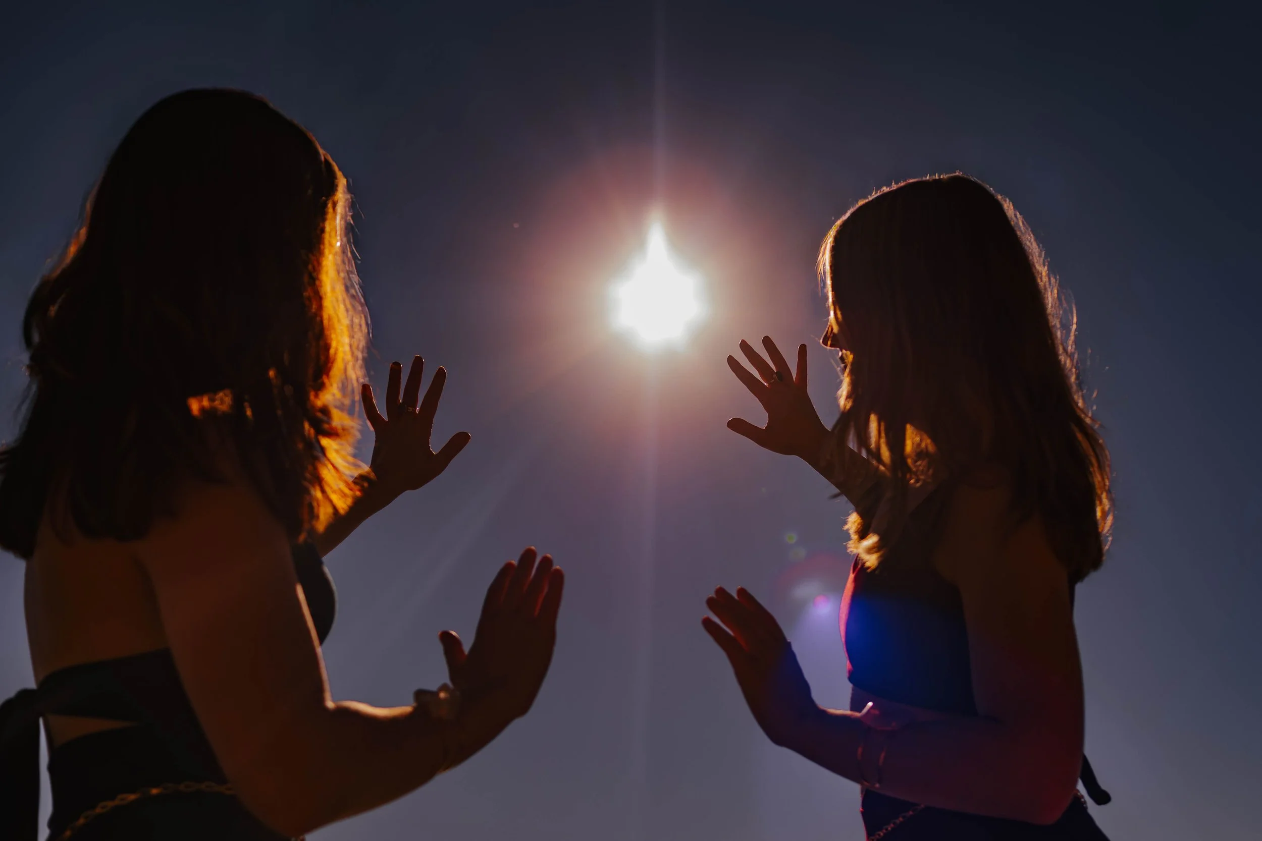 Marley and Lacey look into the Sun with their palms facing the Sun.