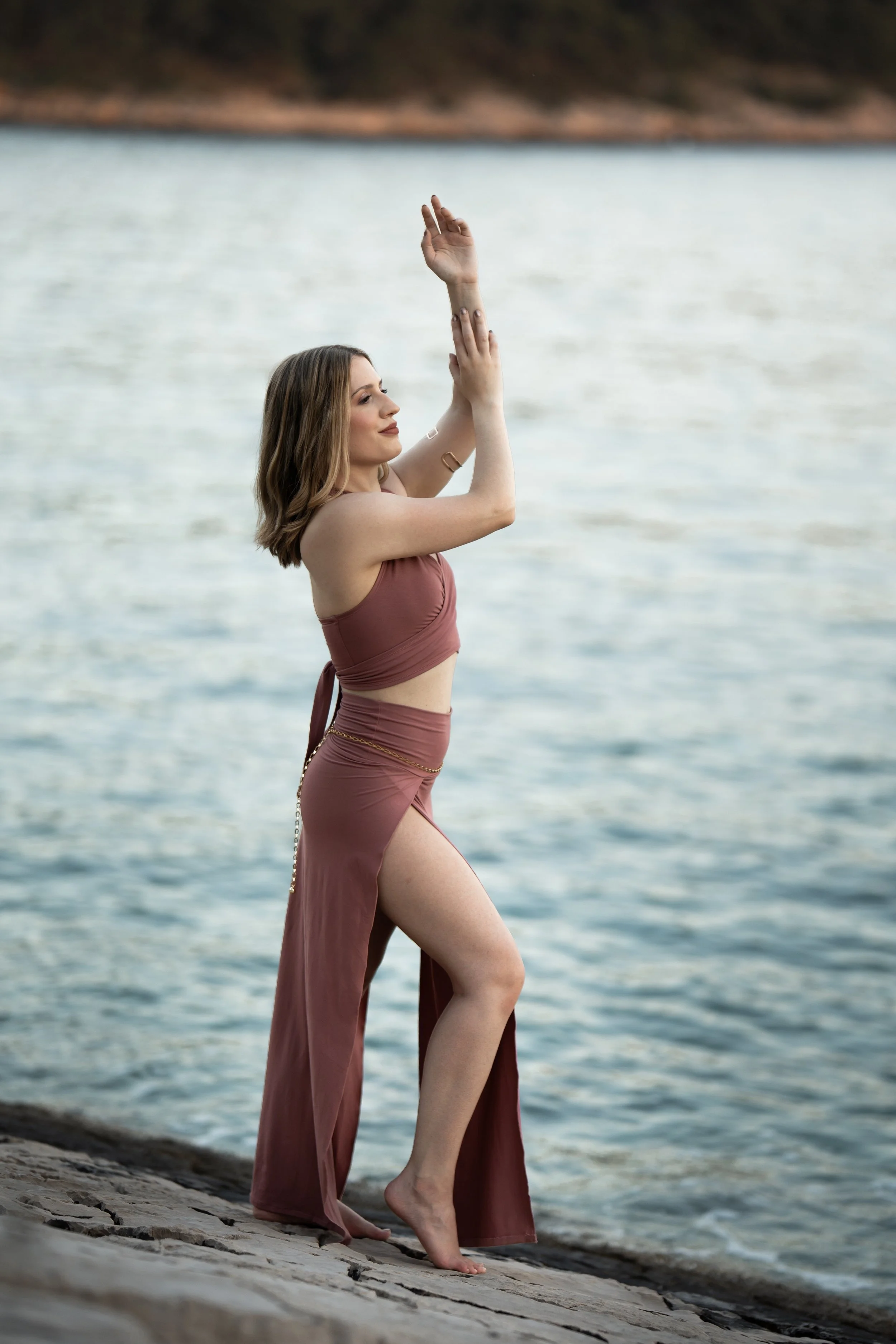 Lacey stands with her arms raised above her head and in front of her body.