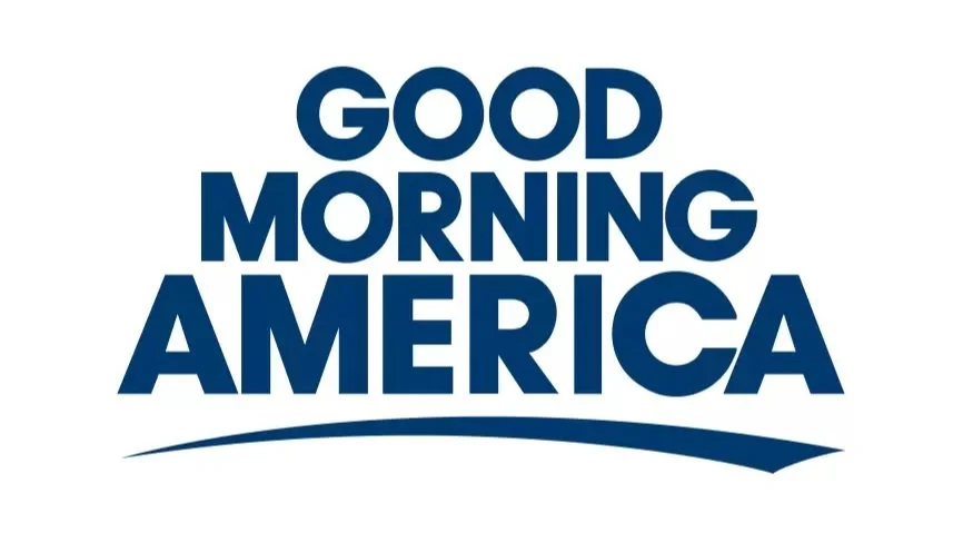 A logo with text stating 'Good Morning America' in bold dark blue letters on a white background, with a curved line underneath.