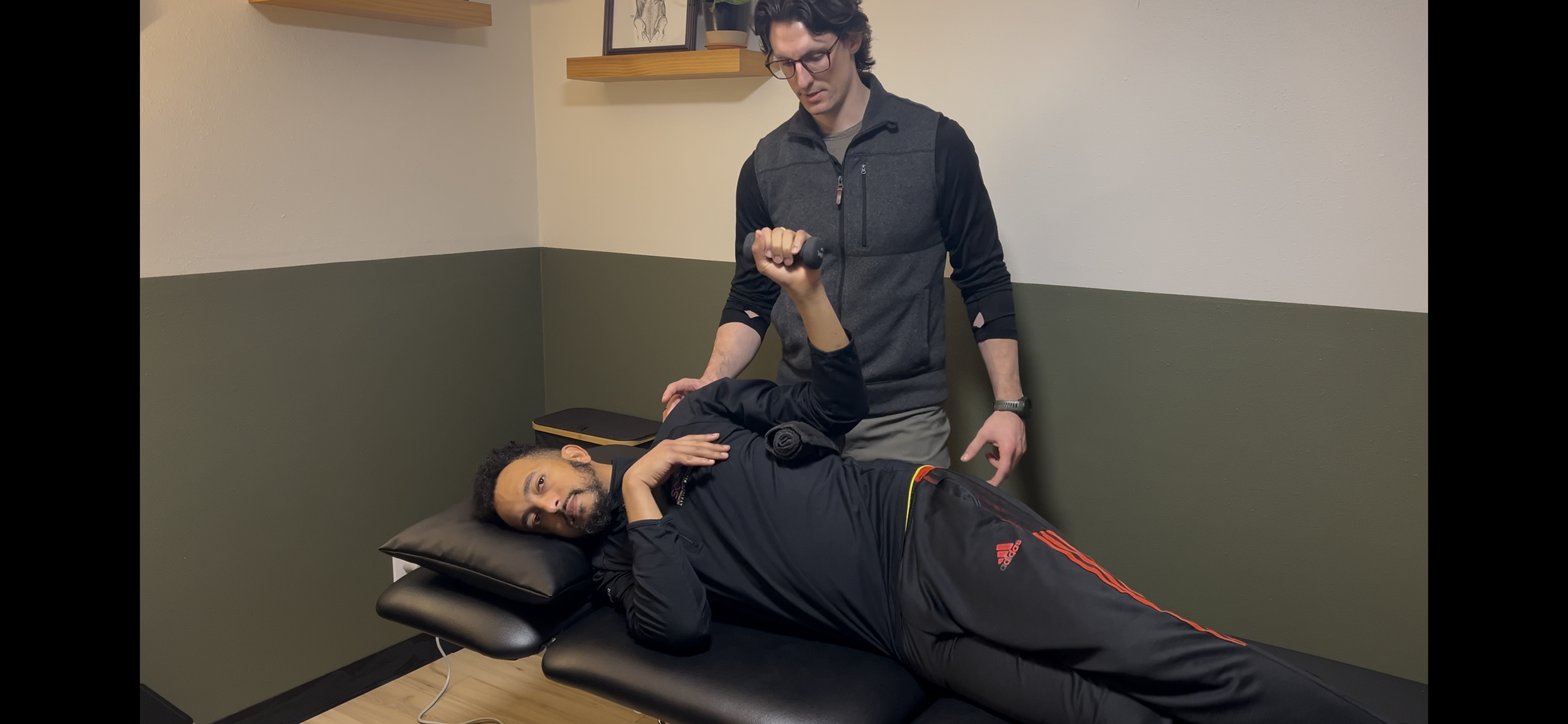 Dr. Ryan Eckert supporting a patient with shoulder external rotation movements in early rehab.