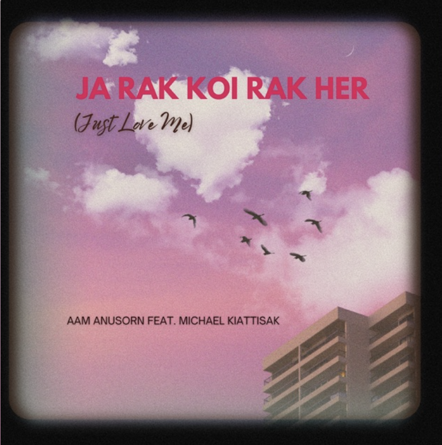Album cover with pink sky, clouds, and flying birds, with a building partially visible at the bottom right corner. The text reads "JA RAK KOI RAK HER (Just Love Me)" with artist credits "AAM ANUSORN FEAT. MICHAEL KIATTISAK".