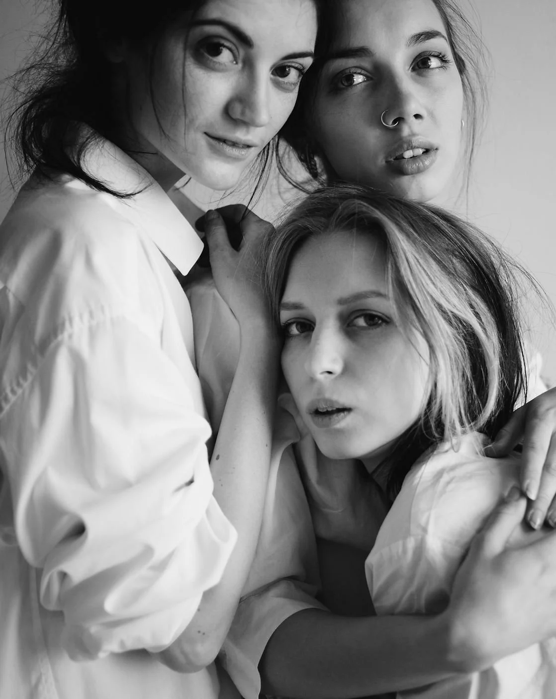 Black and white photograph of three women posing closely and expressively for the camera.