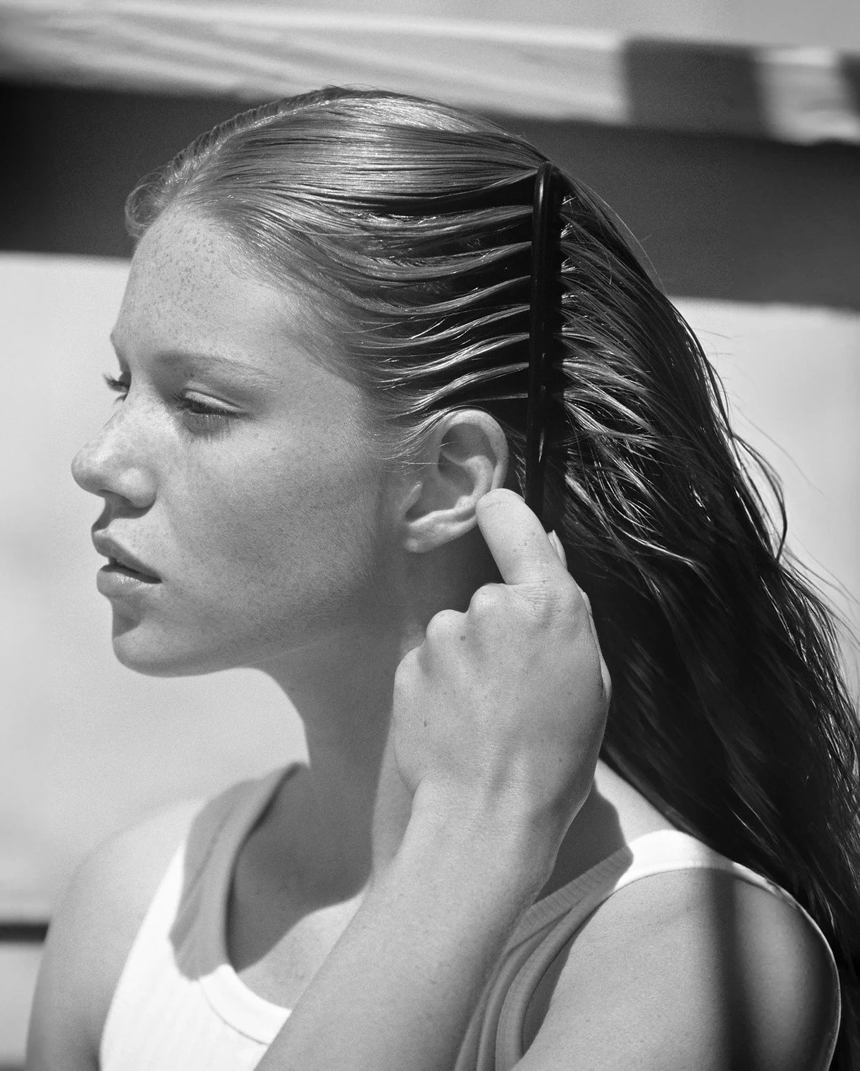 A woman with wet hair using a wide-tooth comb to style her hair.