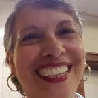 Close-up of a woman smiling with earrings in her ears.